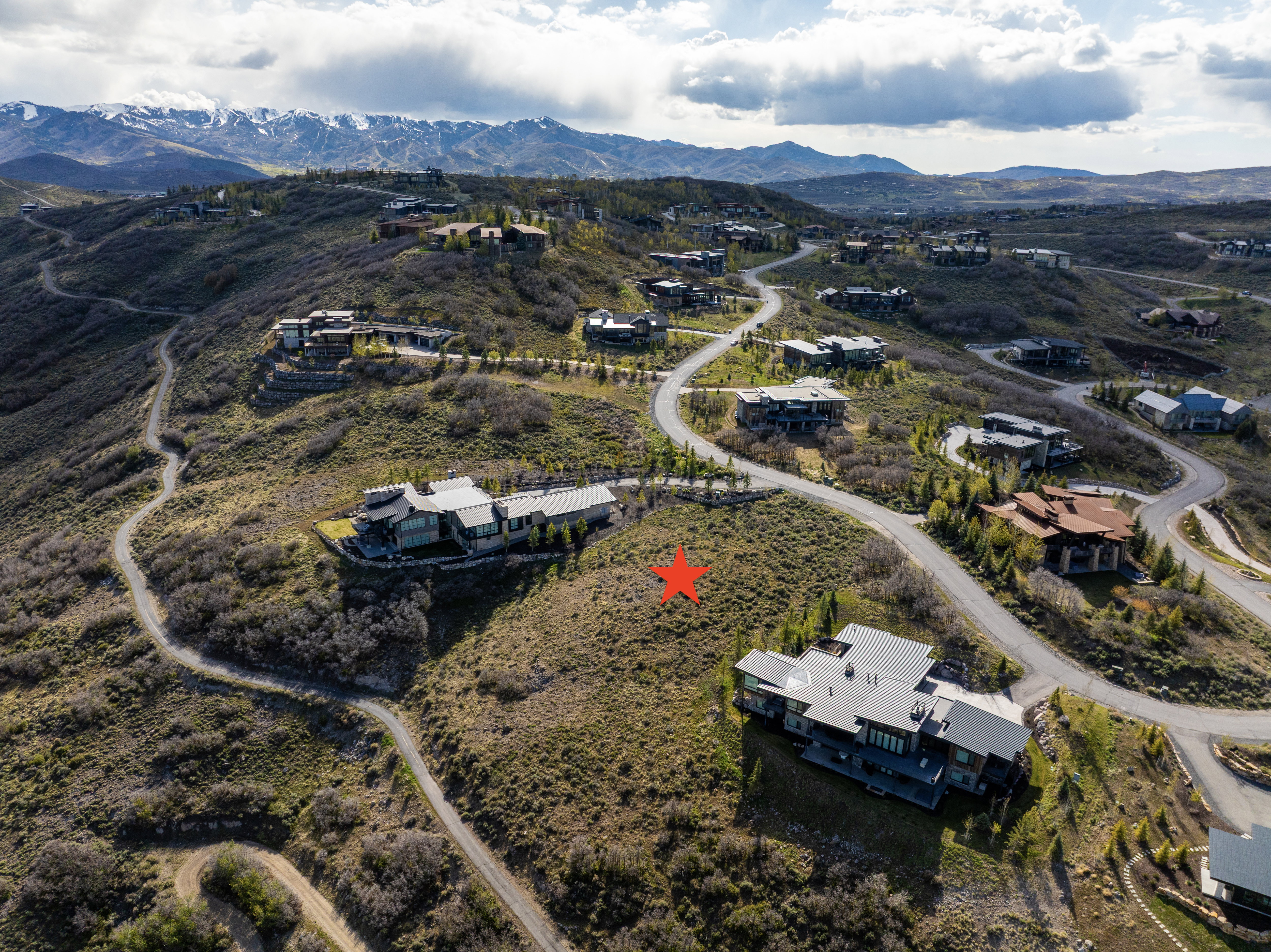 Expansive mountain landscape featuring multiple custom residences and winding roads