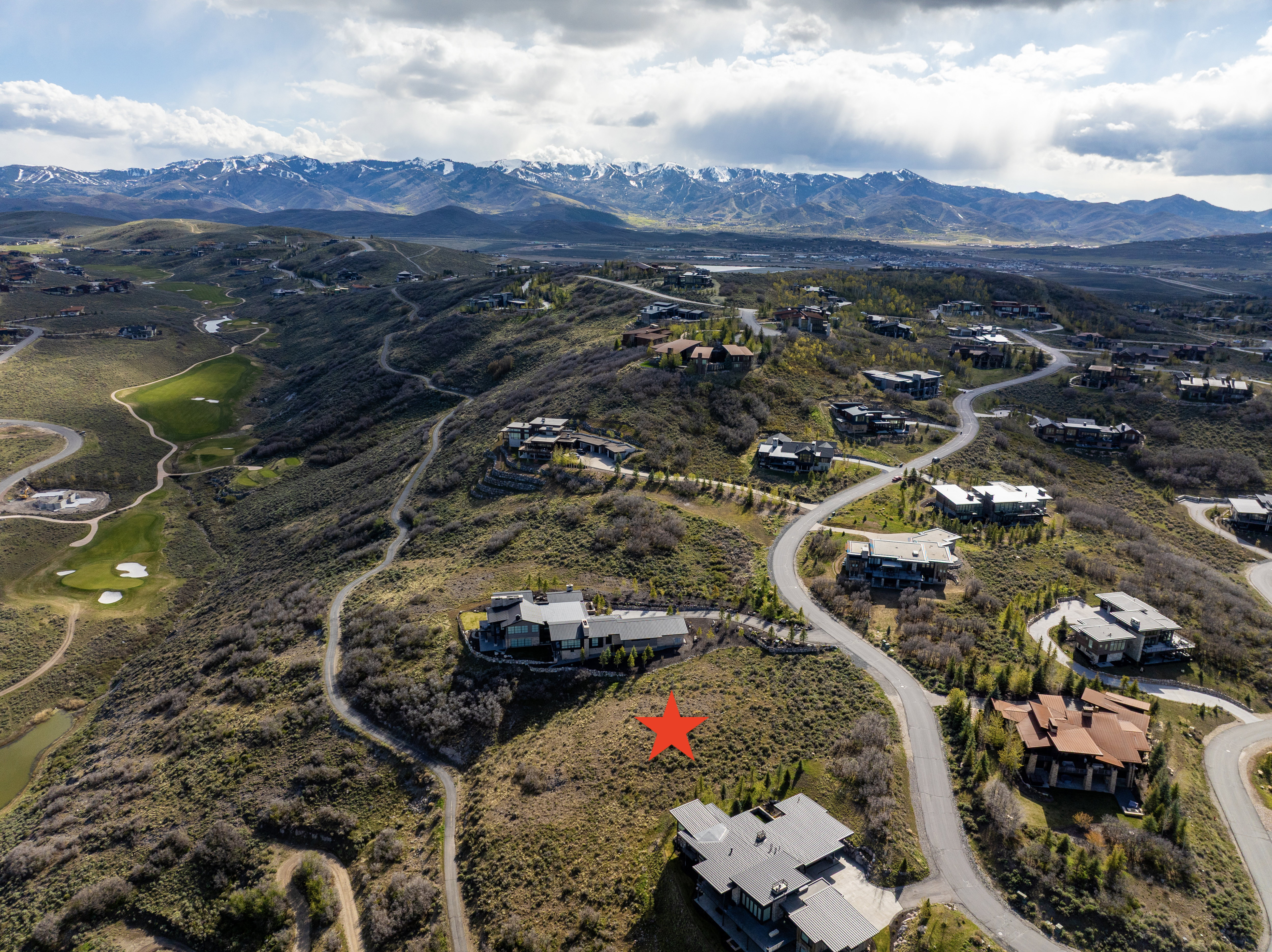 Elevated property site featuring a winding paved road and surrounding residential architecture