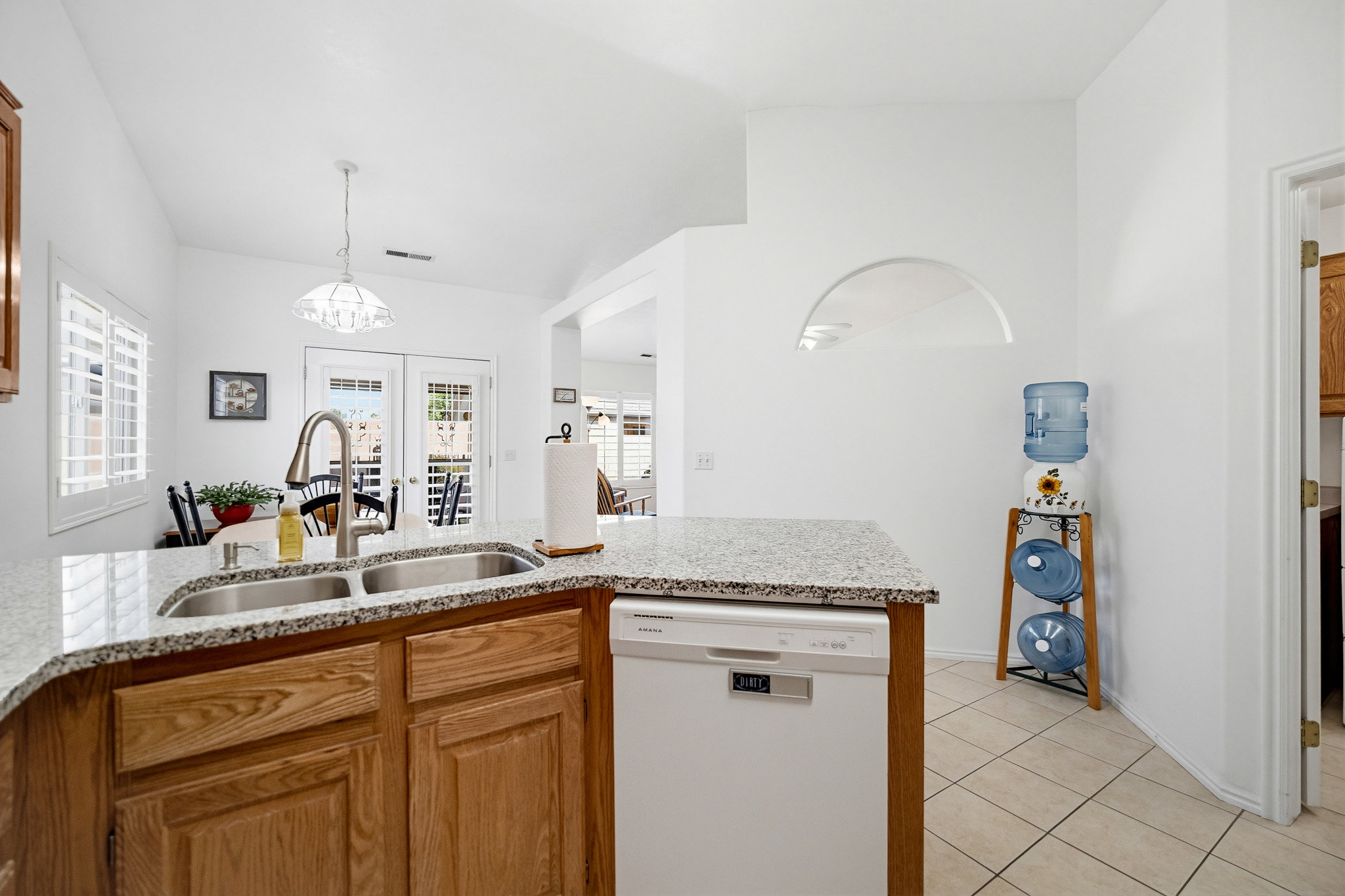 Kitchen featuring a curved granite-style countertop with an undermount double-basin sink and a modern gooseneck faucet