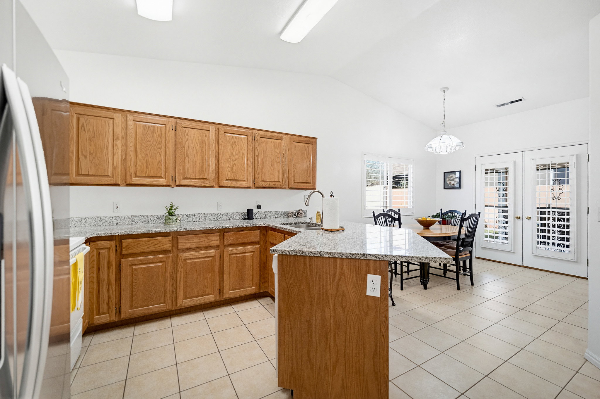 Kitchen featuring wood cabinetry, light-colored countertops, tile flooring, and vaulted ceilings