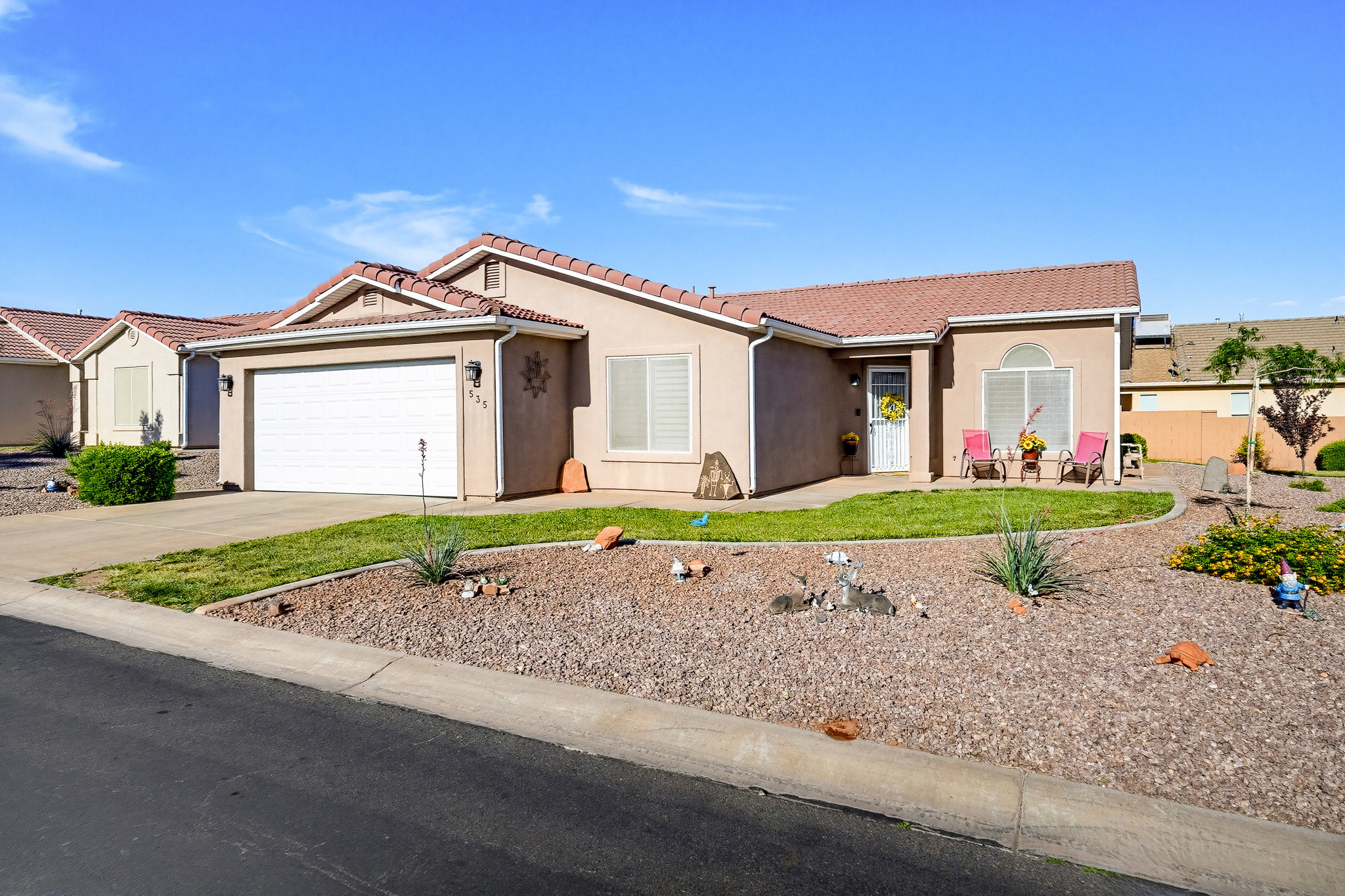 Stucco exterior with a tiled roof, featuring an attached two-car garage and a concrete driveway