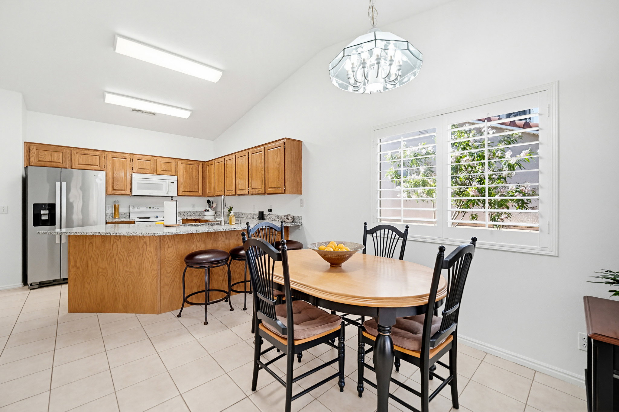 Kitchen and dining area featuring a vaulted ceiling and tile flooring