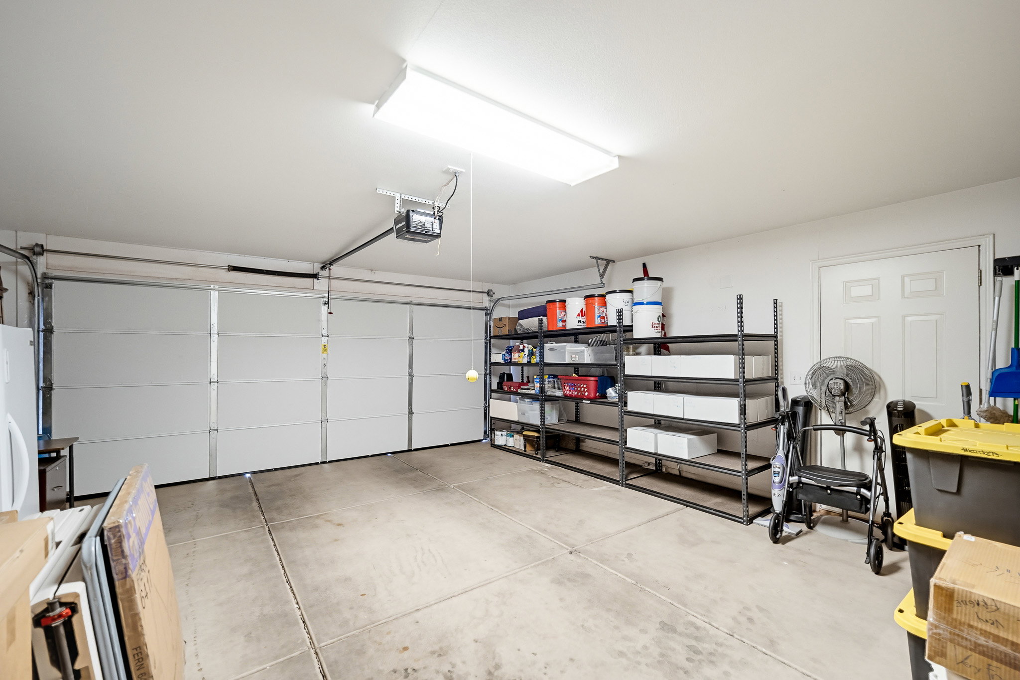 Spacious garage featuring two sectional overhead doors, a finished ceiling, and concrete flooring