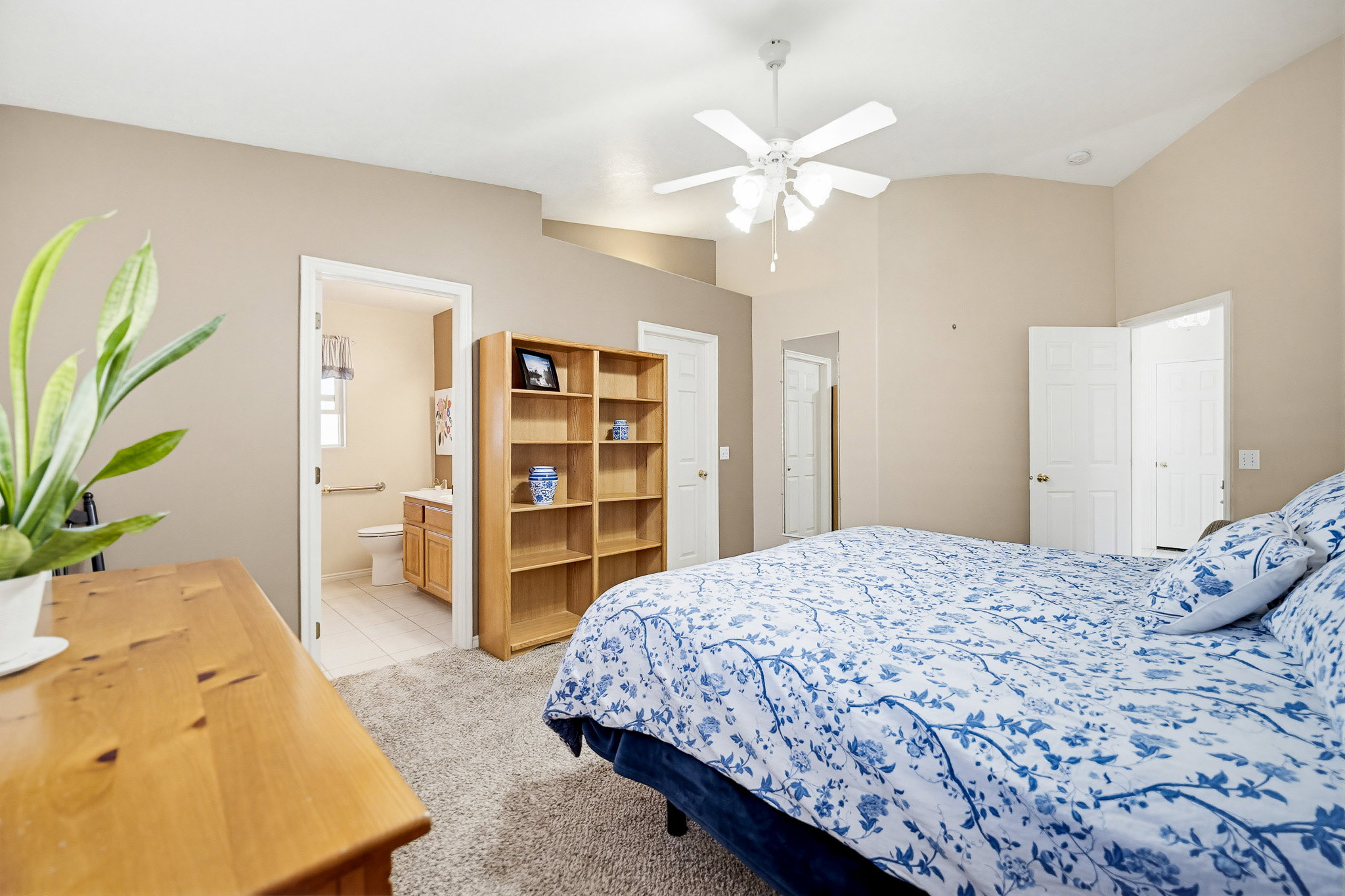 Bedroom featuring vaulted ceilings, a ceiling fan, plush carpeting, and a built-in shelving unit