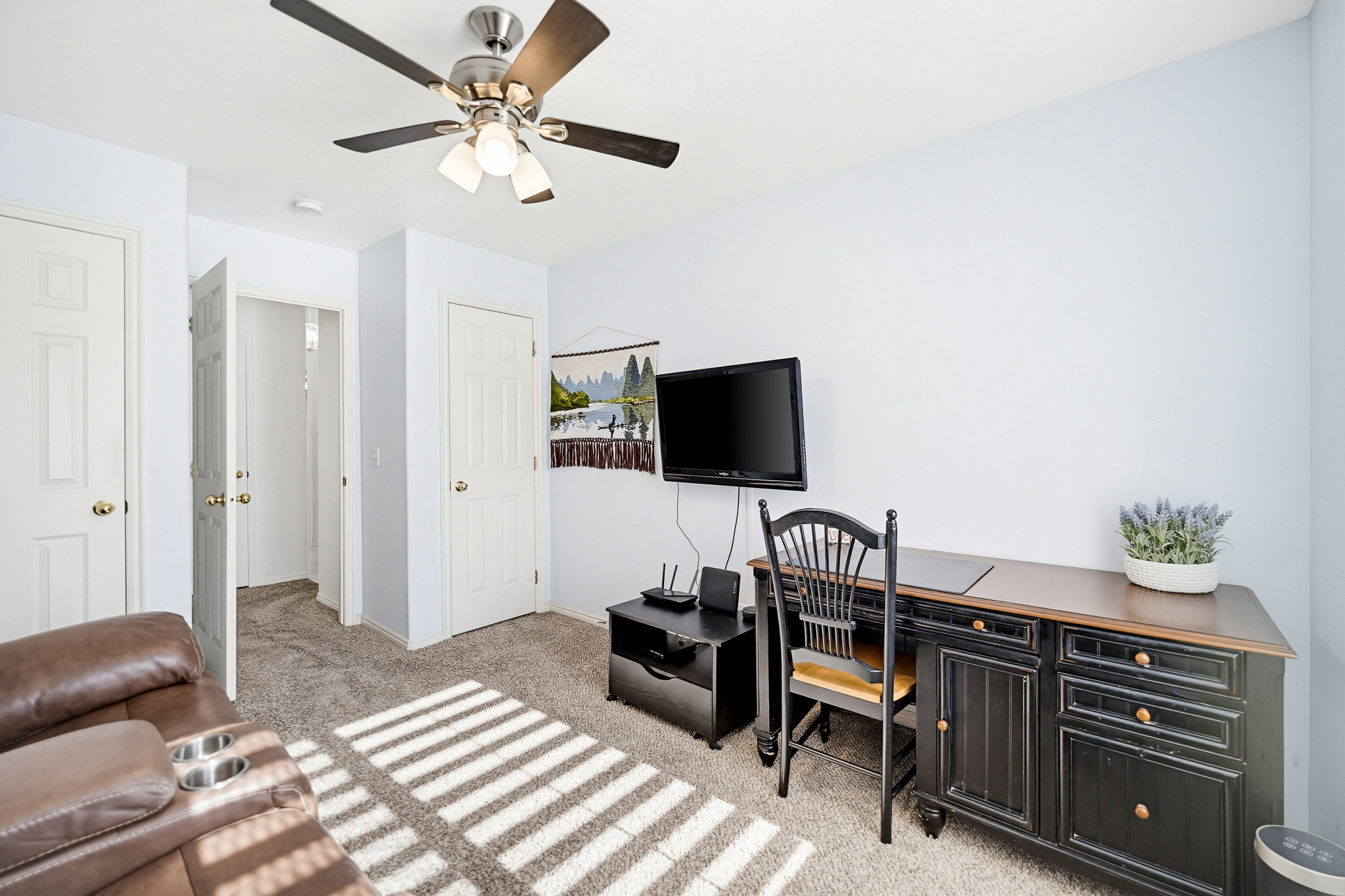 Room featuring a ceiling fan with integrated lighting, multiple paneled doors, and carpet flooring