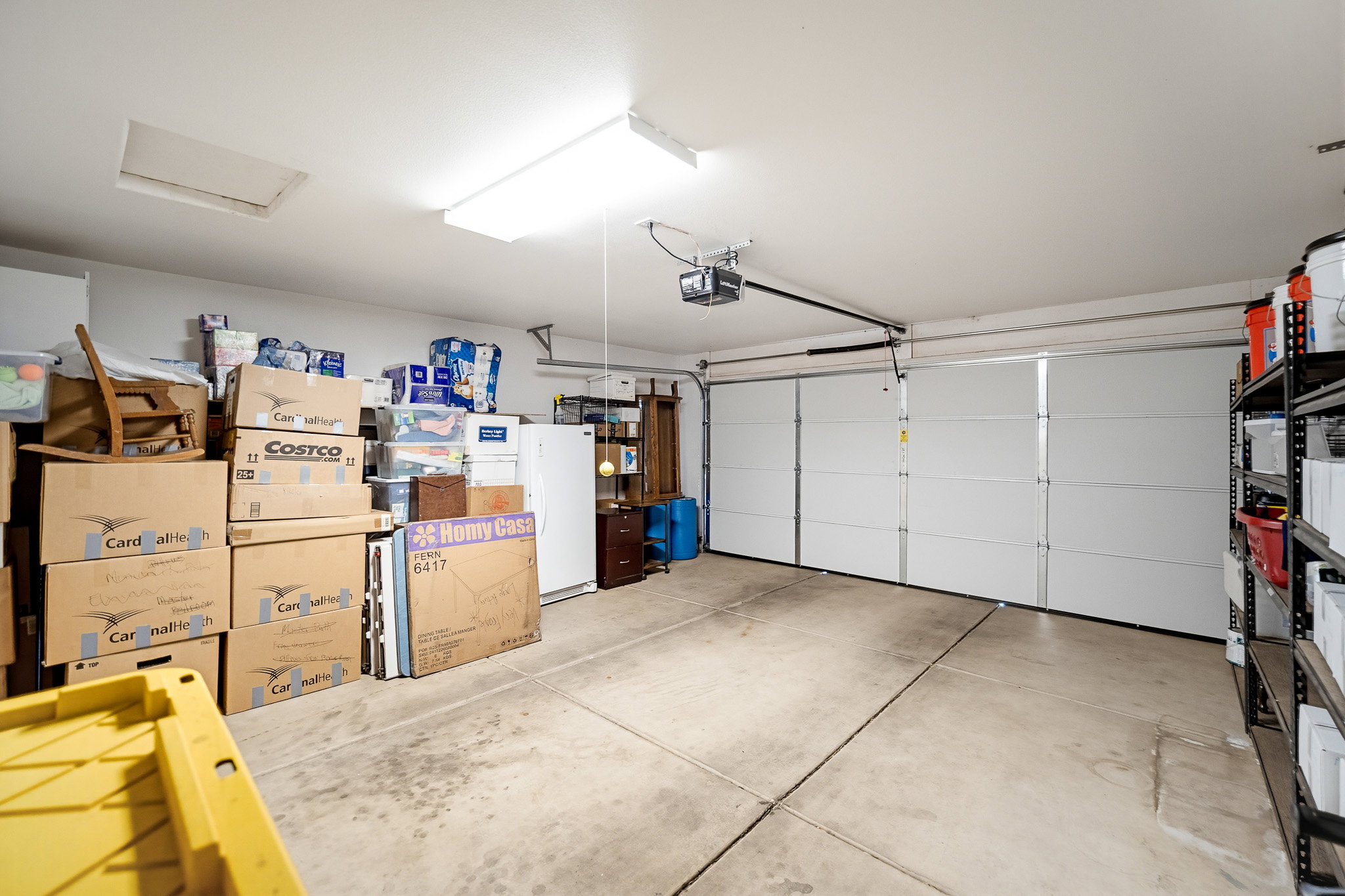 Attached two-car garage featuring a concrete floor, overhead lighting, and an automatic garage door opener