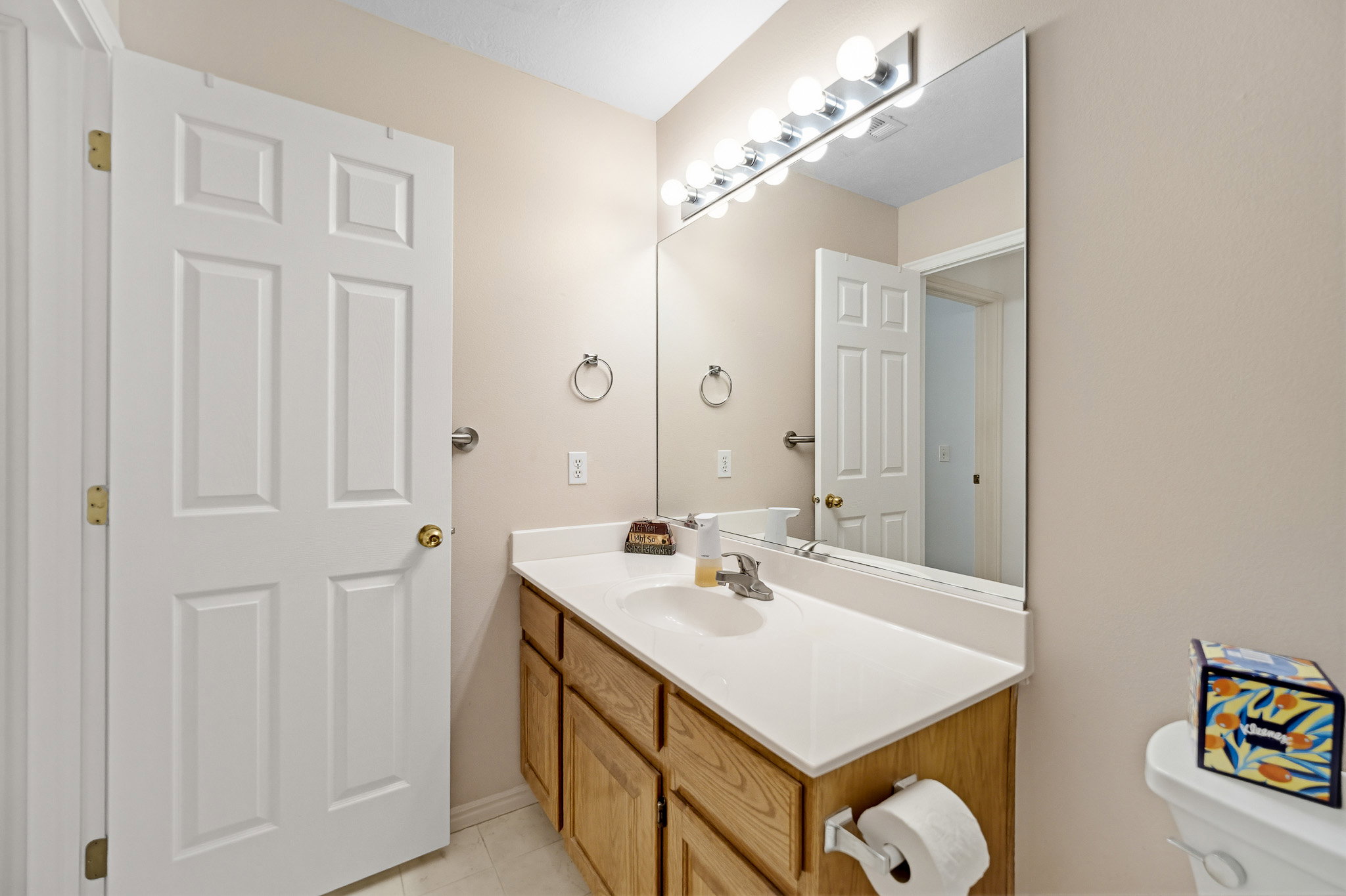 Bathroom vanity with a white countertop, undermount sink, and wood-finish cabinetry