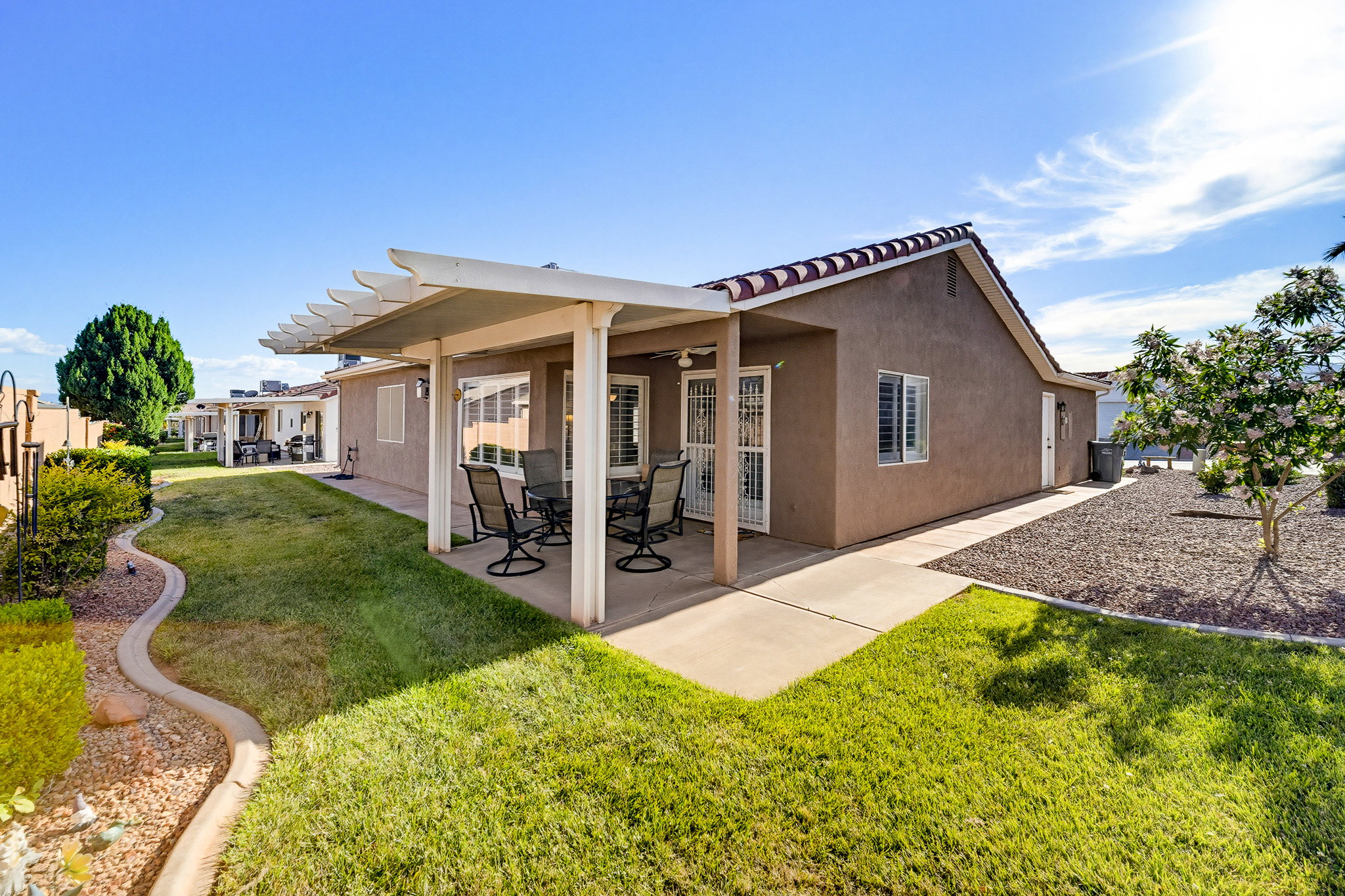 Expansive rear patio featuring a full-length pergola, concrete slab, and stucco exterior