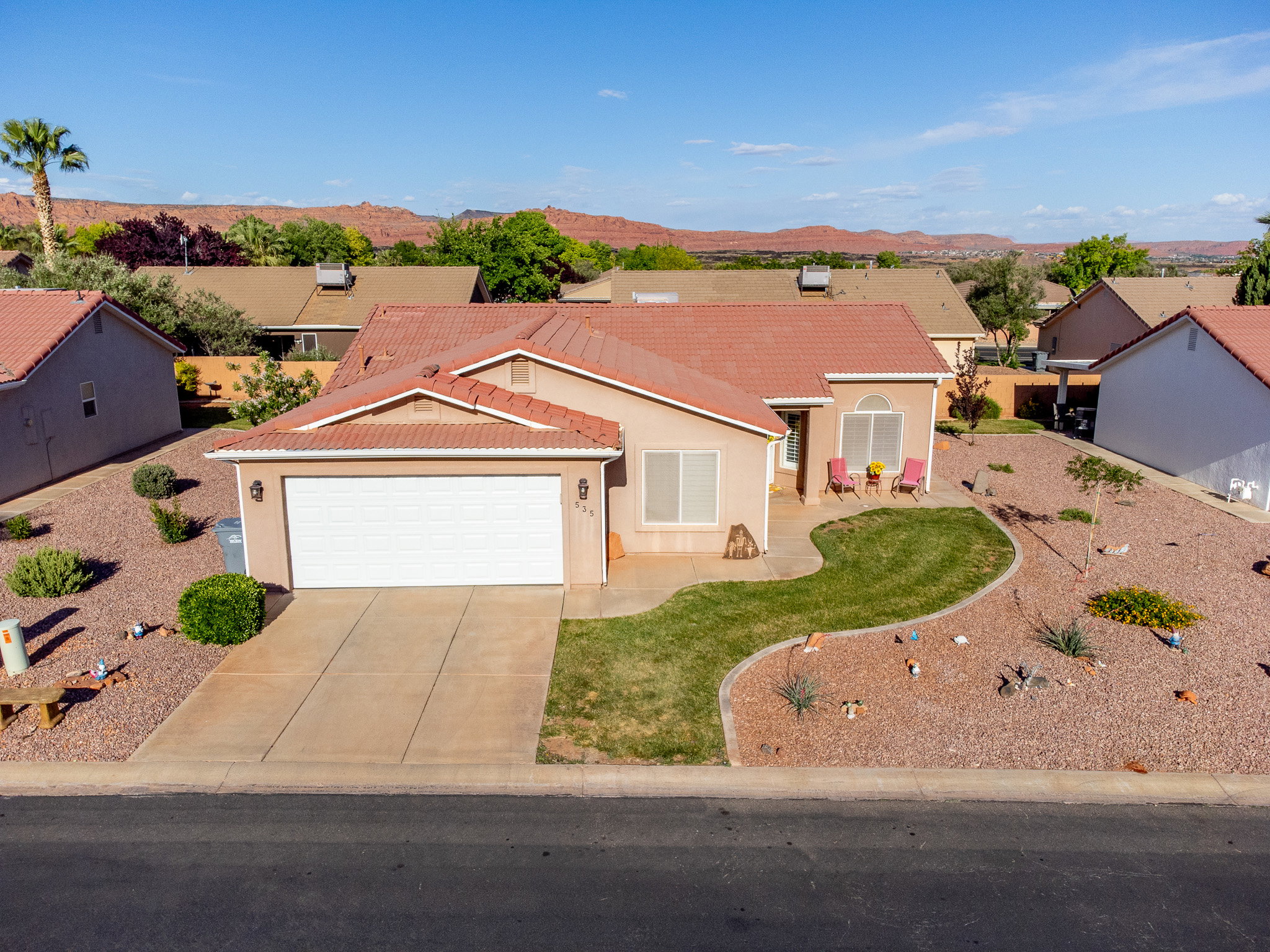 Single-story residence featuring a terracotta-hued tile roof, attached two-car garage, and a concrete driveway