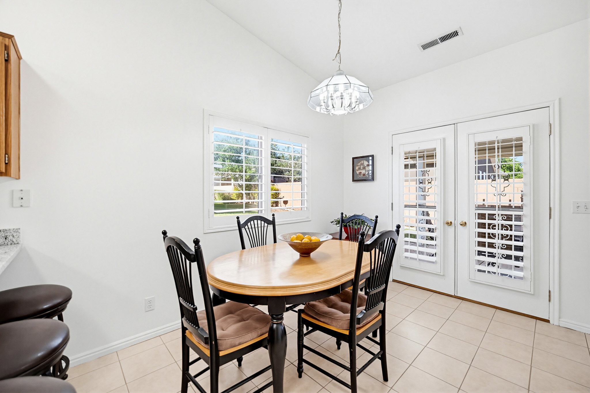 Dining area featuring vaulted ceilings, light tile flooring, and a decorative pendant light fixture