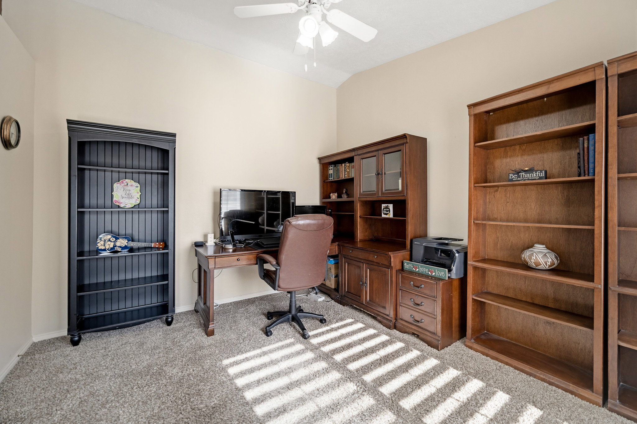Carpeted room with vaulted ceiling and a ceiling fan