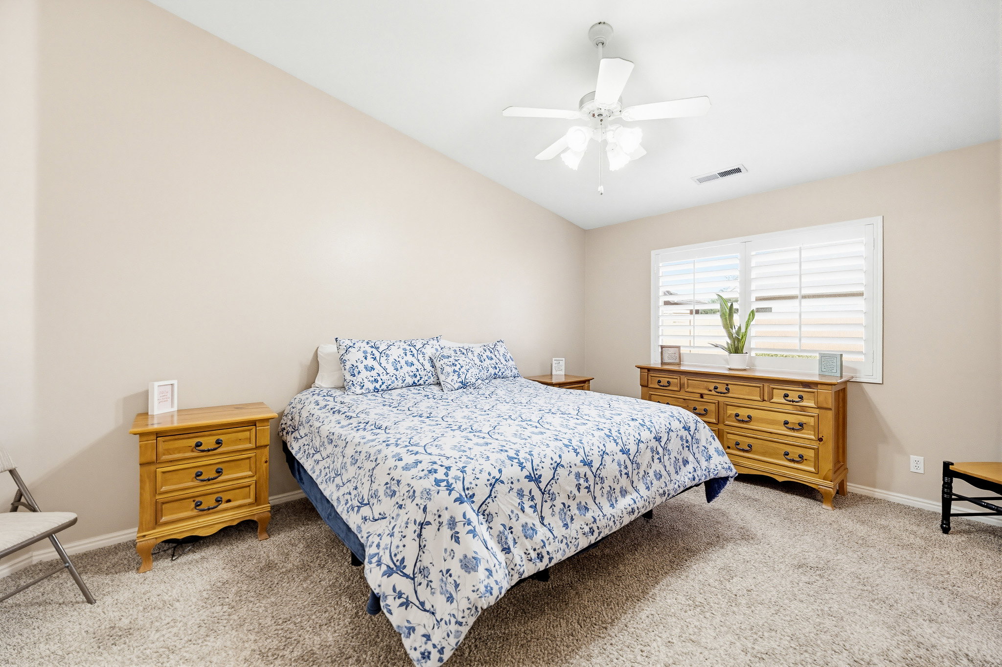 Comfortable bedroom featuring vaulted ceilings, a ceiling fan, and carpeted flooring