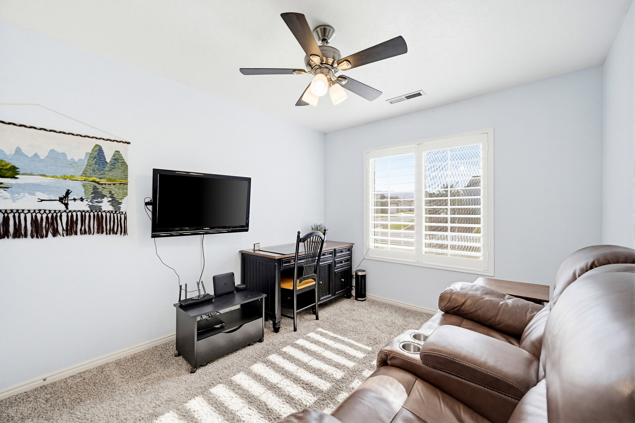 Carpeted room featuring a ceiling fan with integrated lighting, a window with plantation shutters, and light-toned wall finishes