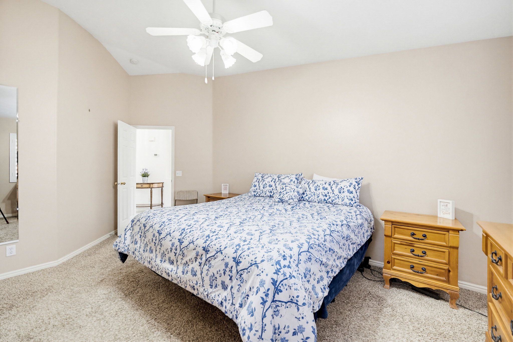 Carpeted bedroom featuring vaulted ceilings and a ceiling fan with light fixture