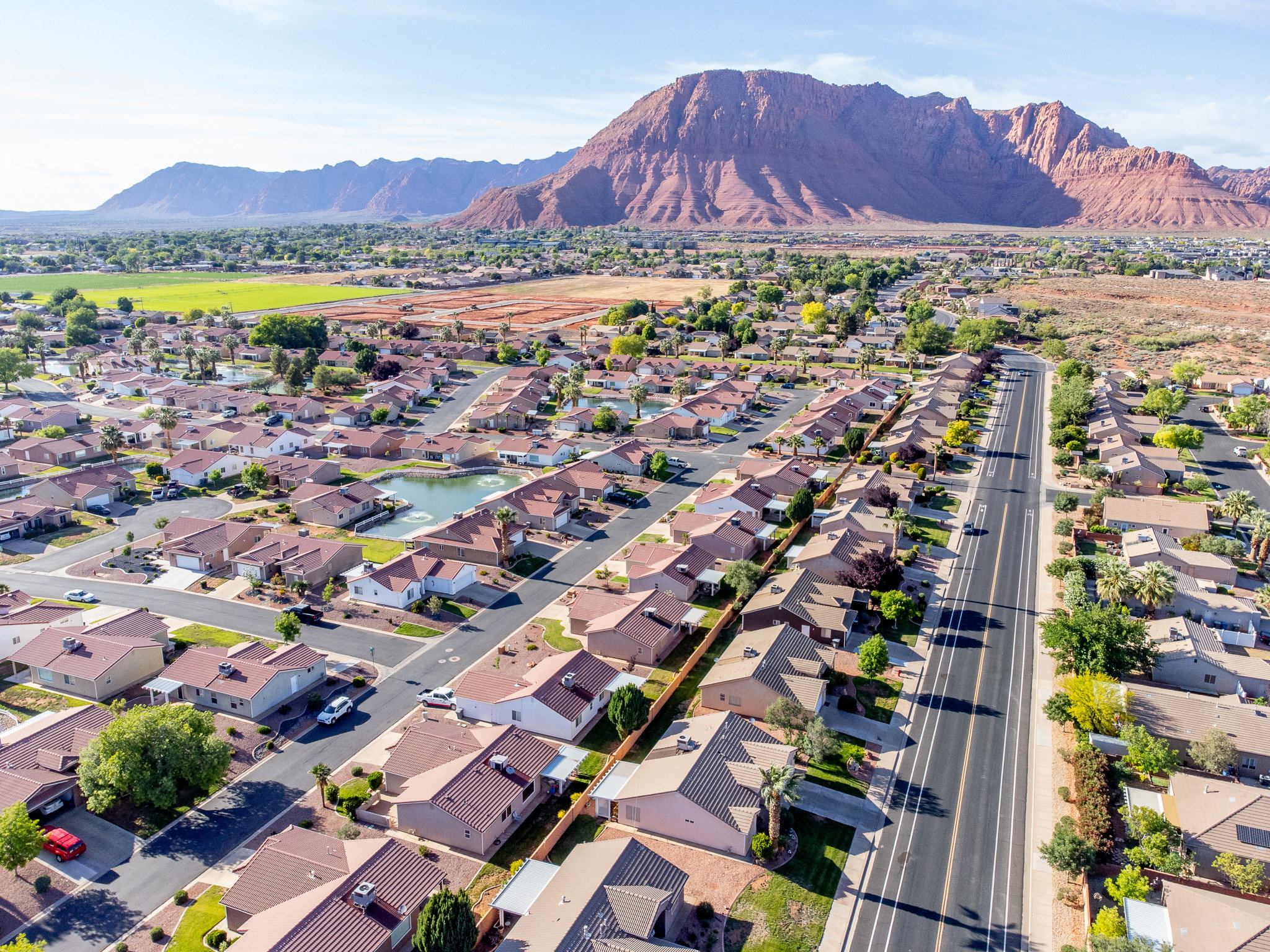 Expansive aerial perspective showcasing a residential development with a large red rock mountain range as a prominent backdrop