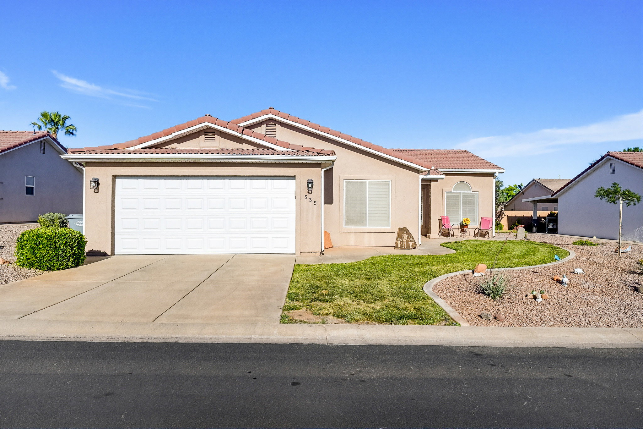 Stucco exterior residence featuring a two-car garage, concrete driveway, and a tile roof