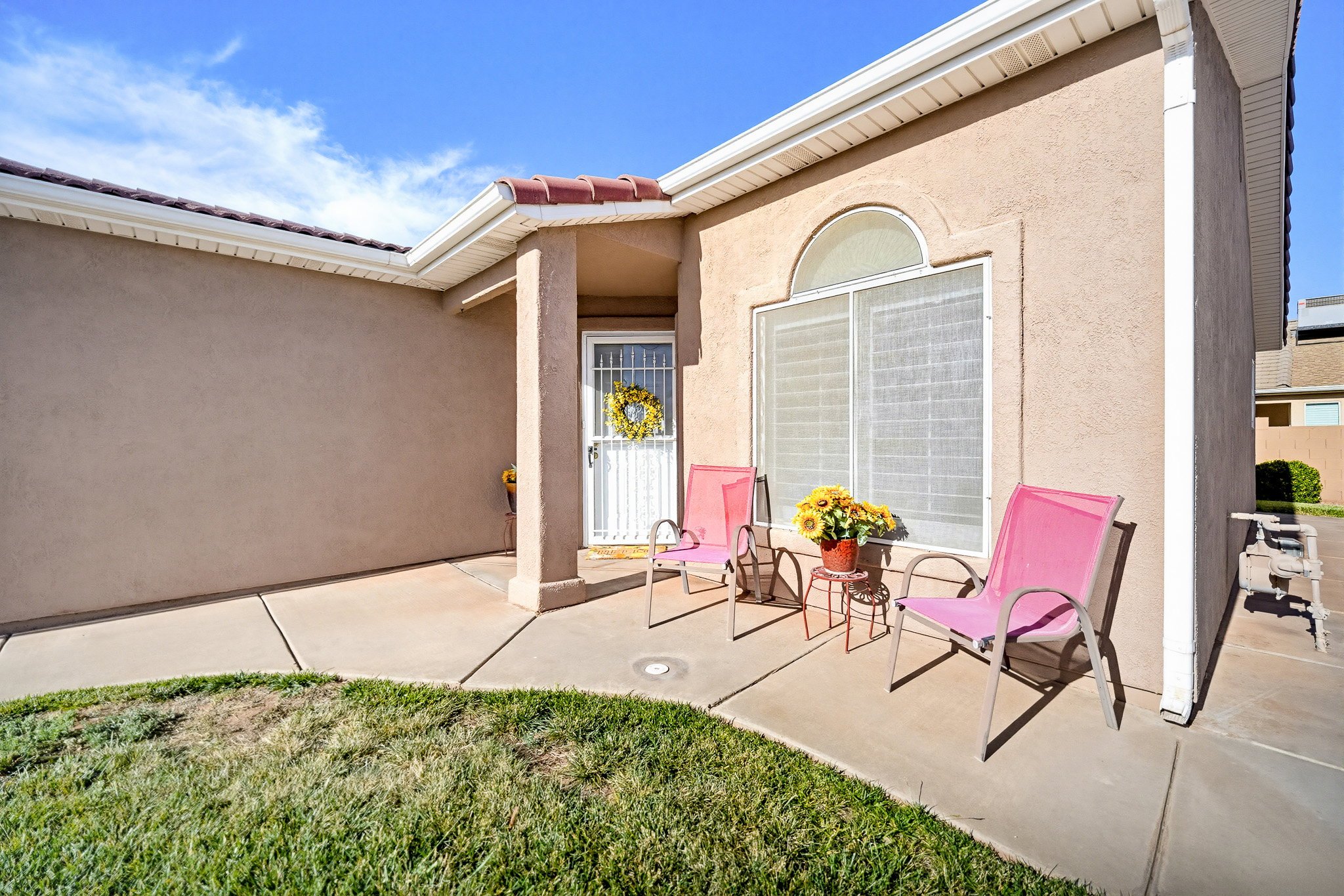 Stucco exterior featuring an arched transom window, covered entry, concrete patio, and red tile roof accents