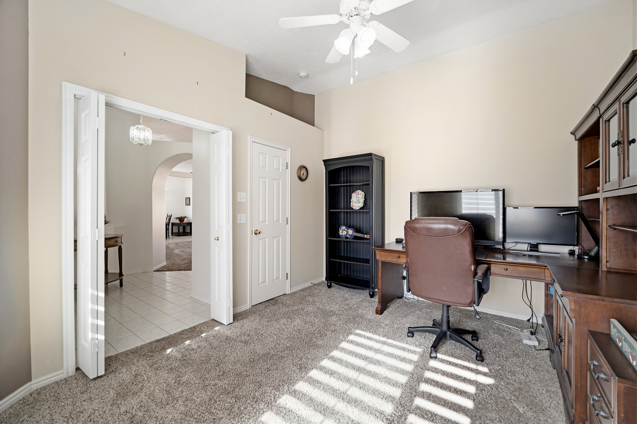 Carpeted room featuring a ceiling fan, bifold doors, and a paneled door