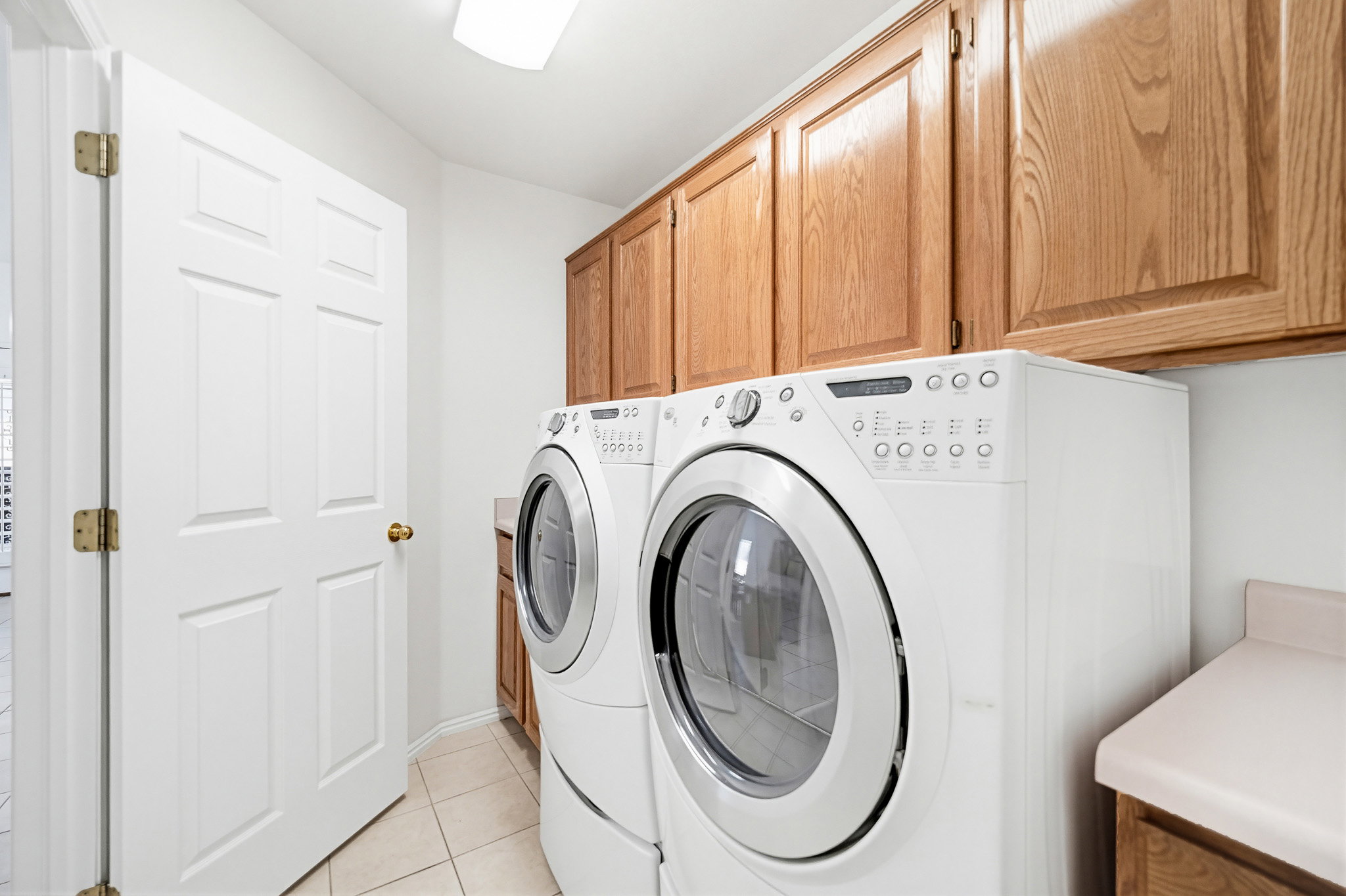 Laundry area featuring extensive wood cabinetry, tile flooring, and a built-in countertop