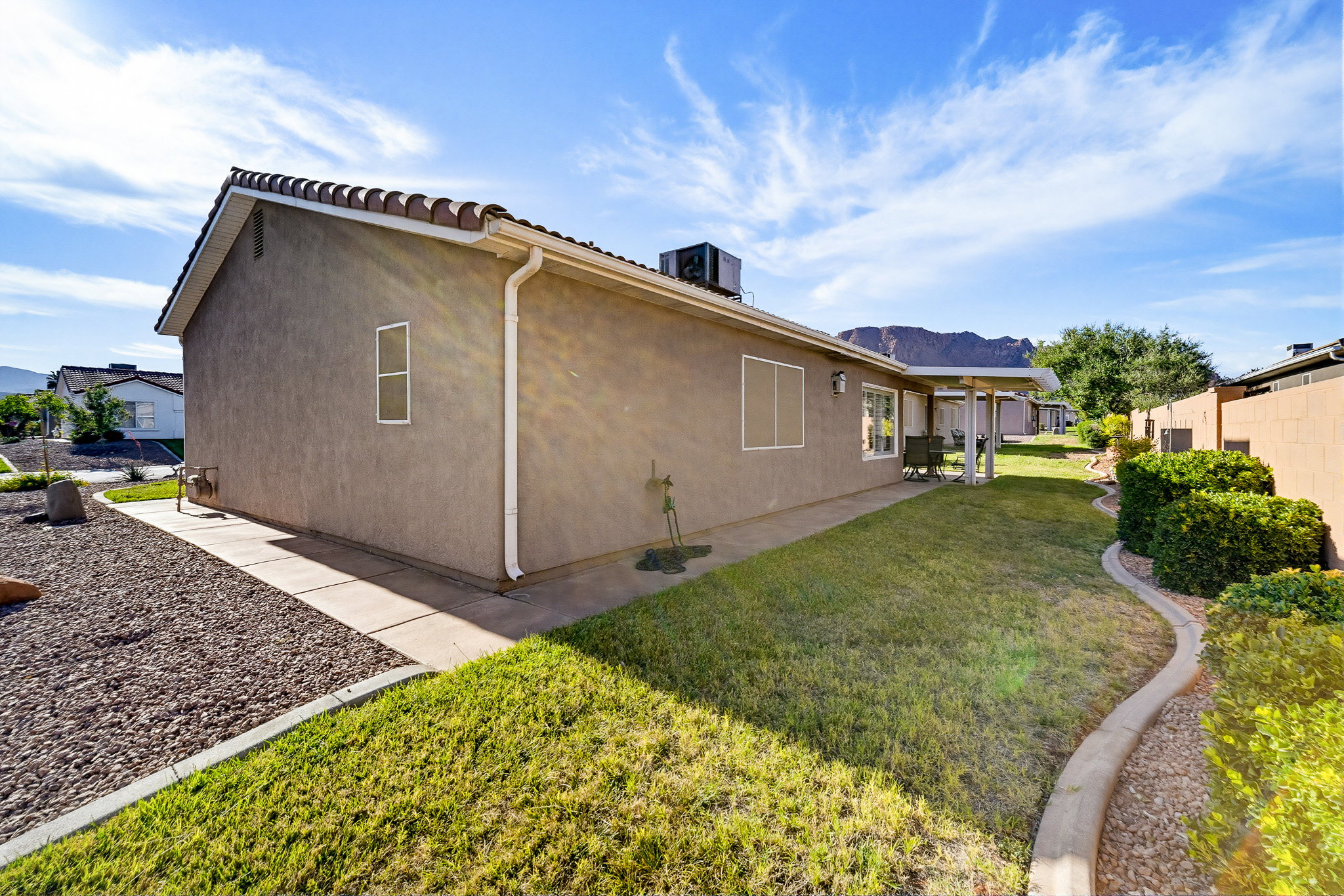 Landscaped exterior featuring stucco siding, a concrete tile roof, and a covered patio area