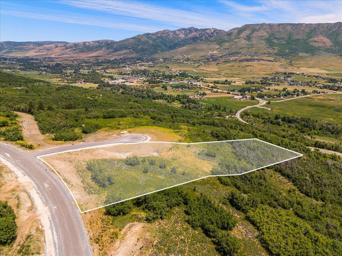 Aerial view of property and surrounding area featuring property boundaries highlighted and a mountainous background