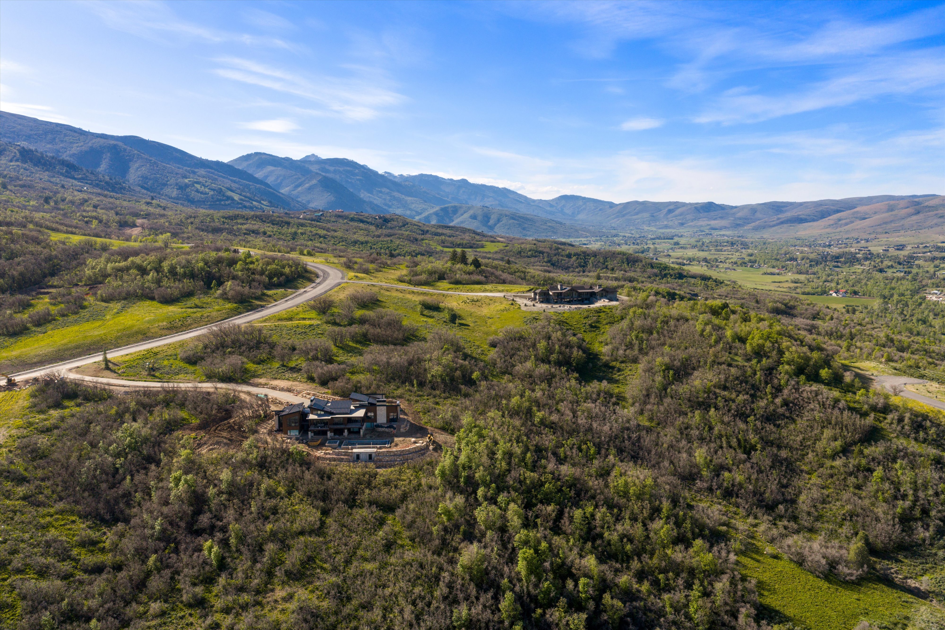Expansive mountain landscape with a modern architectural residence featuring a dark facade and multiple terraces