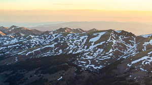 Mountainous terrain featuring snow-dusted peaks and verdant lower slopes