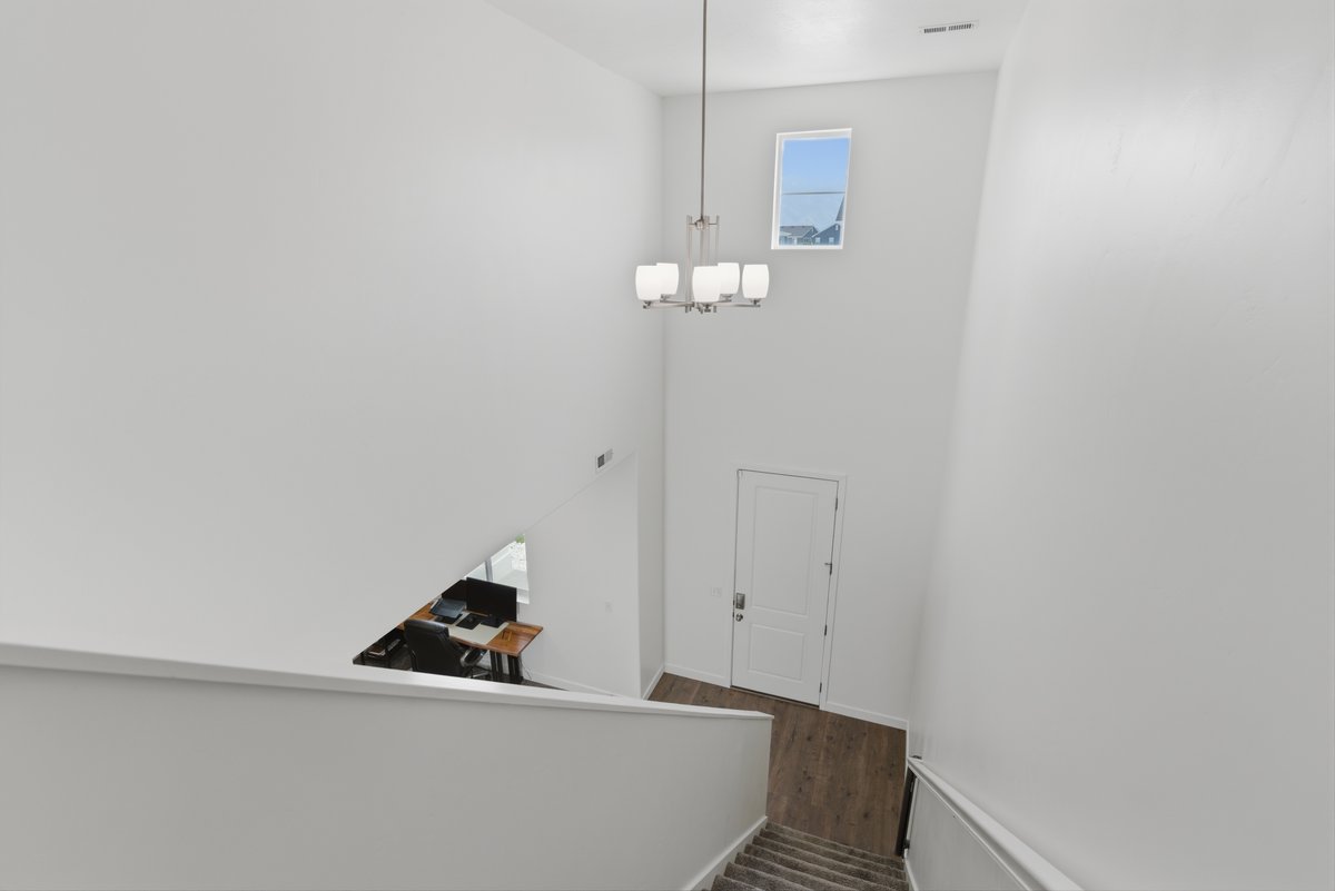 Stairwell with high ceilings, contemporary chandelier, upper transom window, wood-finish flooring, and carpeted stairs