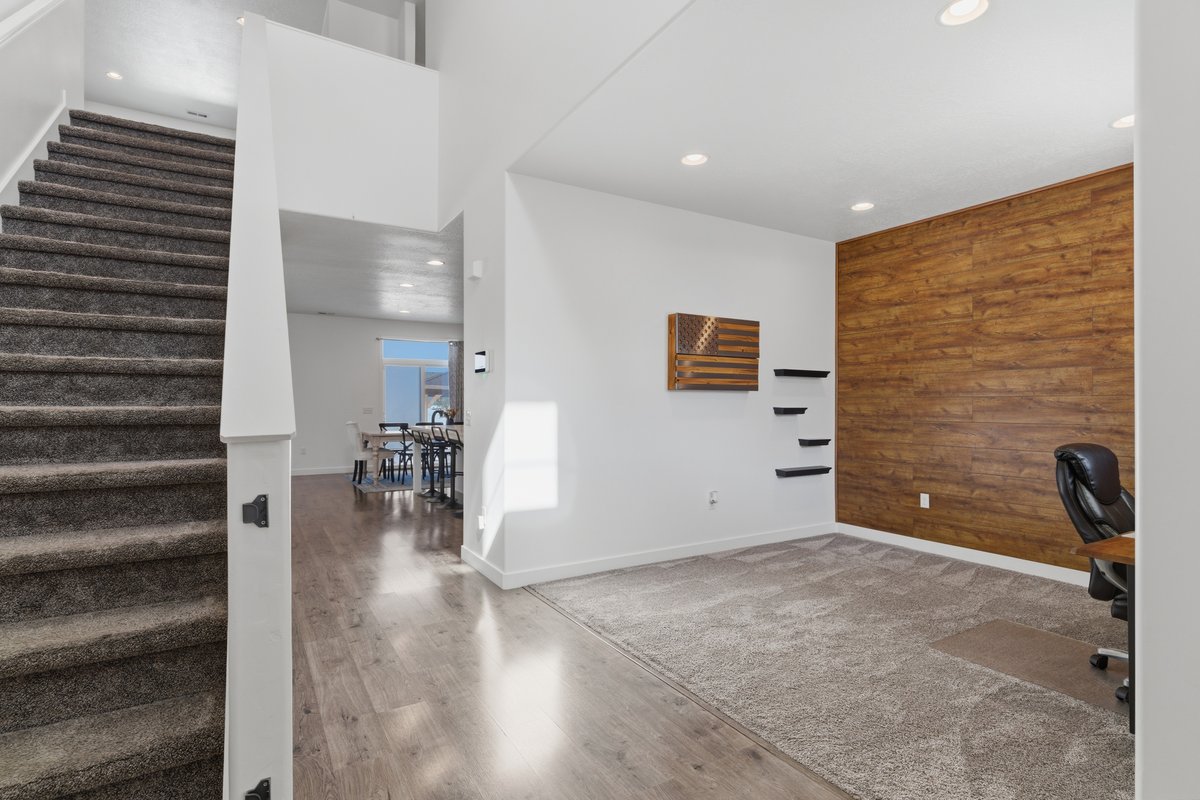 Spacious main level featuring a wood-finish accent wall, recessed lighting, and a neutral carpeted area