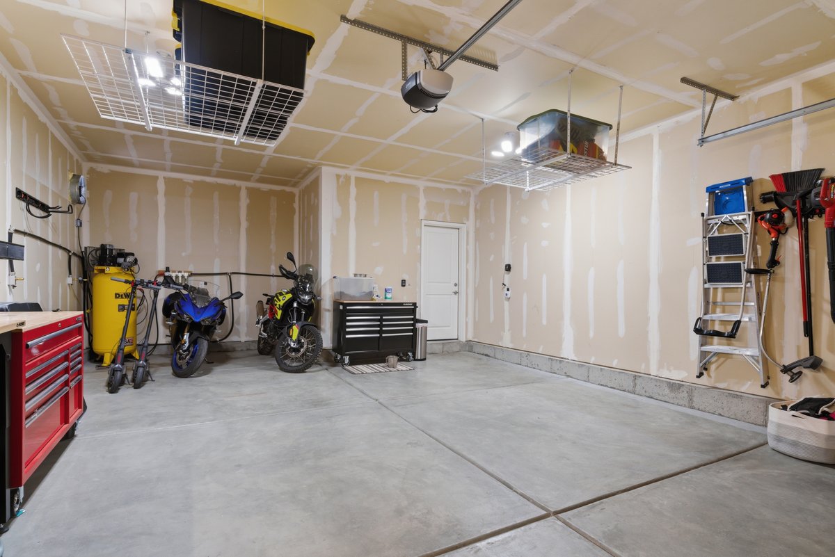 Spacious garage featuring a concrete floor, overhead storage racks, a side entry door, and exposed stud walls