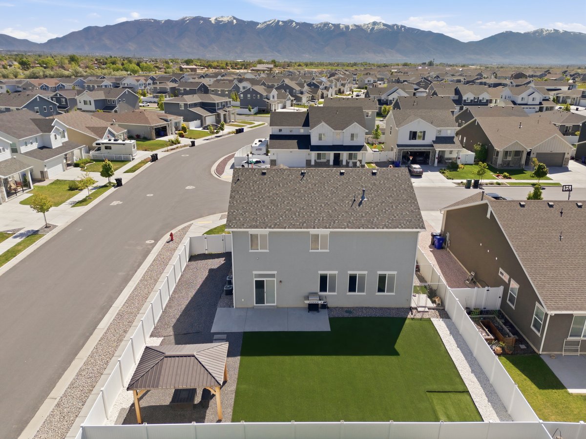 Expansive backyard featuring artificial turf, a concrete patio, and a dedicated pergola structure