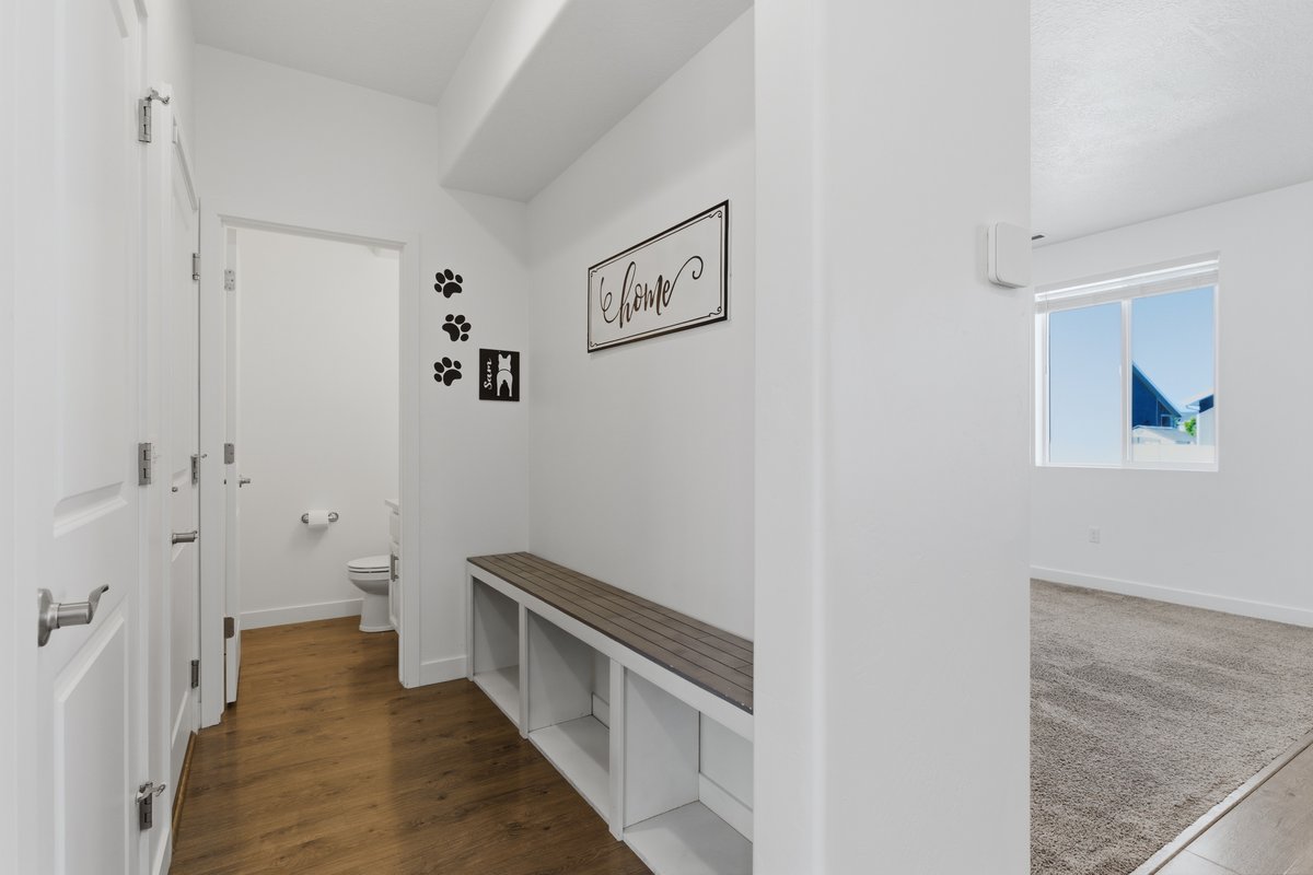 Entryway featuring wood-finish flooring, a built-in bench with integrated shelving, and a nearby half-bath