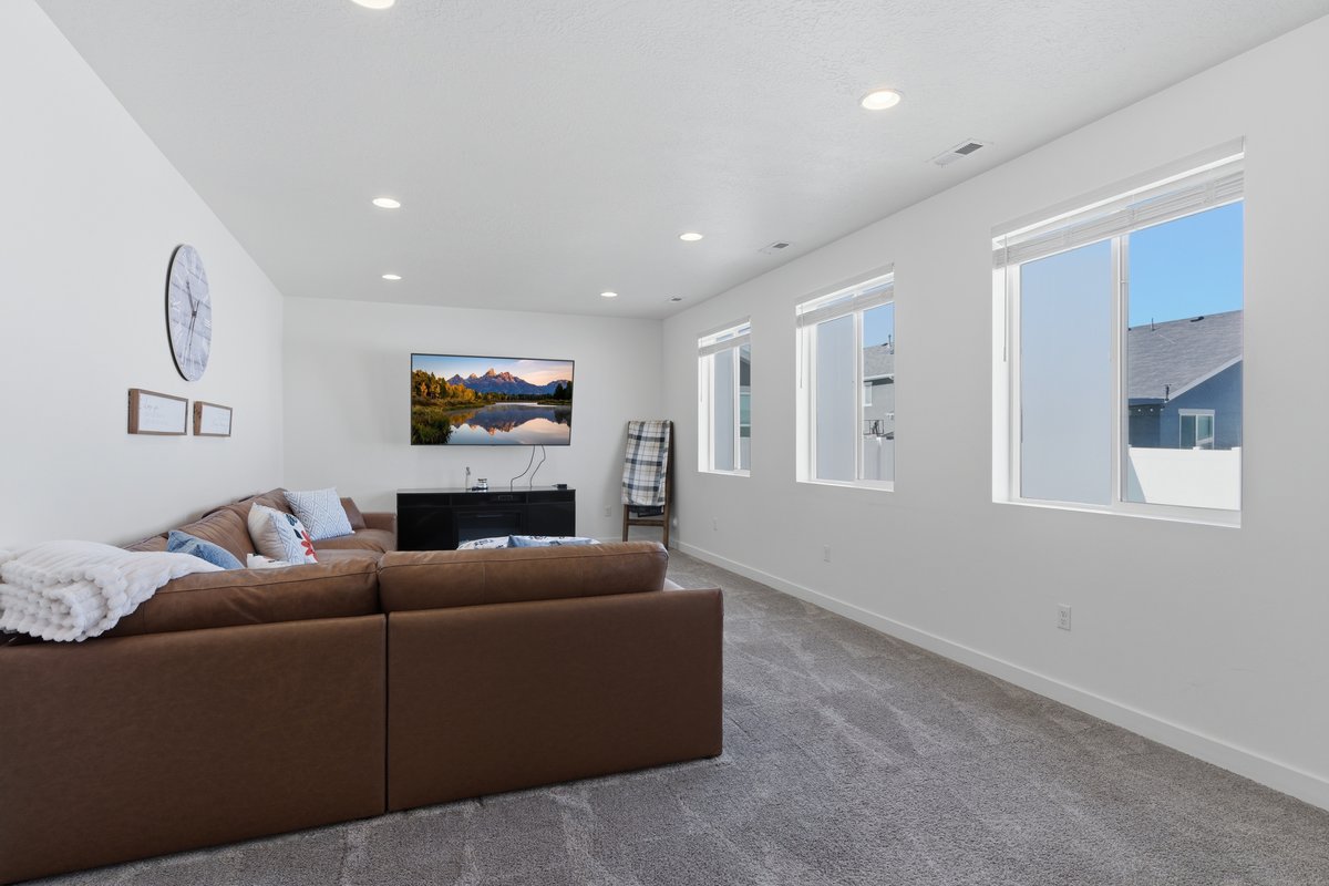 Spacious room featuring light gray carpet, white walls, and multiple windows