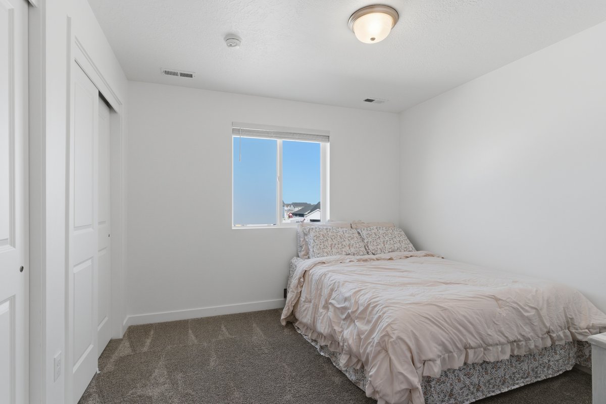 Carpeted room featuring a double bi-fold closet, a single window, and a flush-mount ceiling light fixture