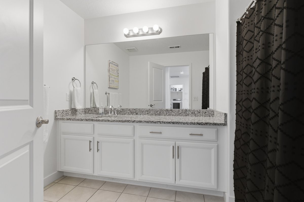 Bathroom vanity featuring a light granite countertop, a single undermount sink with a chrome faucet, and white cabinetry with brushed nickel hardware