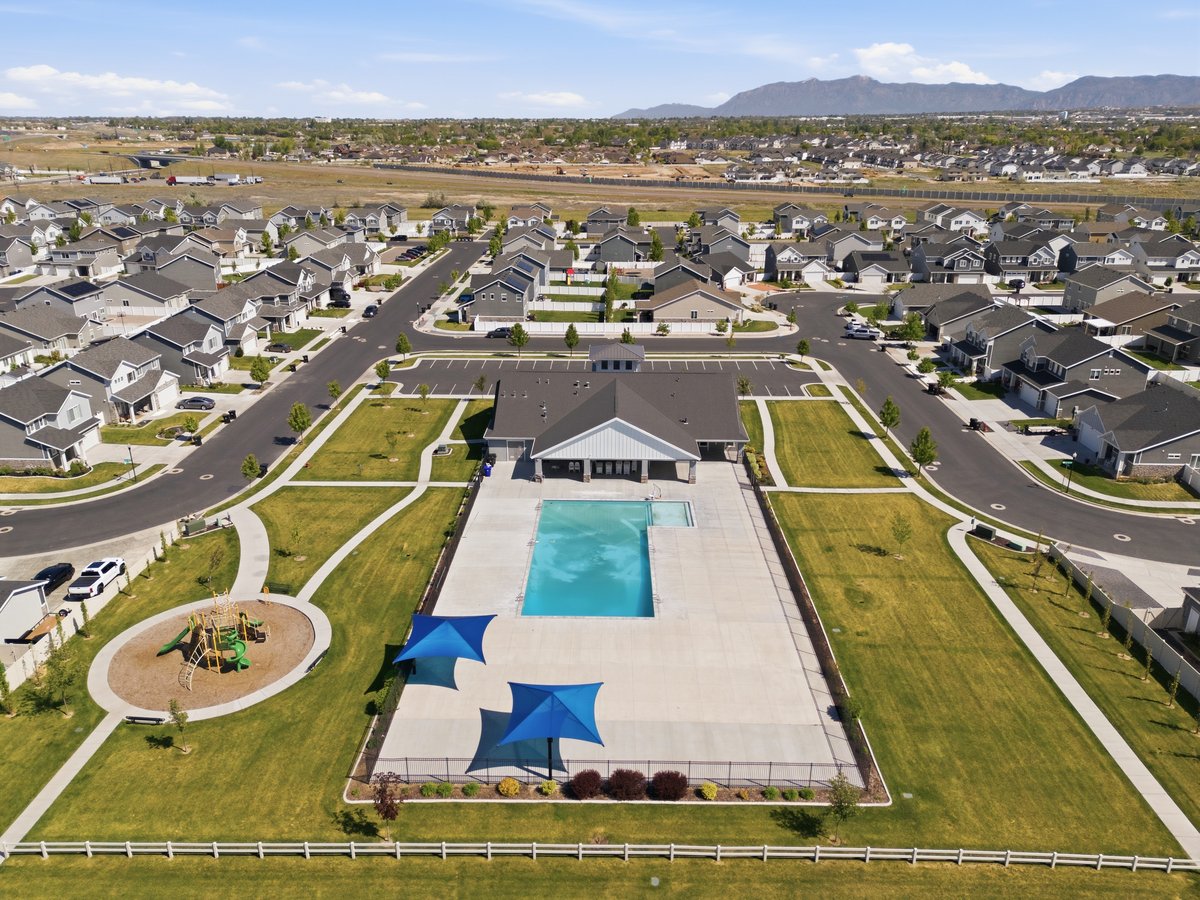 Outdoor swimming pool with expansive concrete decking, shaded lounge areas, and a nearby playground