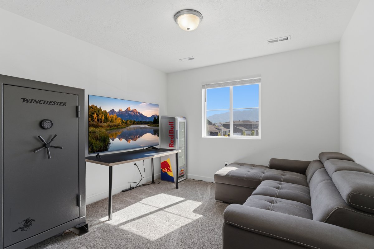 Carpeted room featuring a large window, a ceiling light fixture, a built-in wall vent, and neutral wall tones