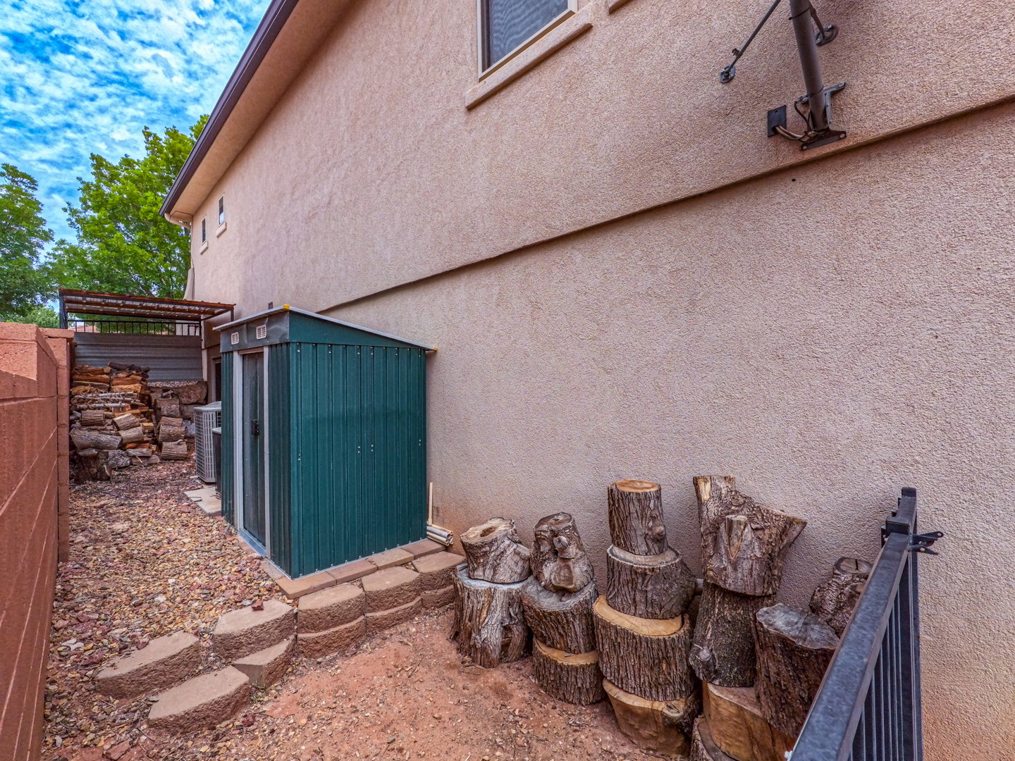 Exterior side yard featuring a metal storage shed, stacked retaining wall blocks, and a crushed rock ground cover