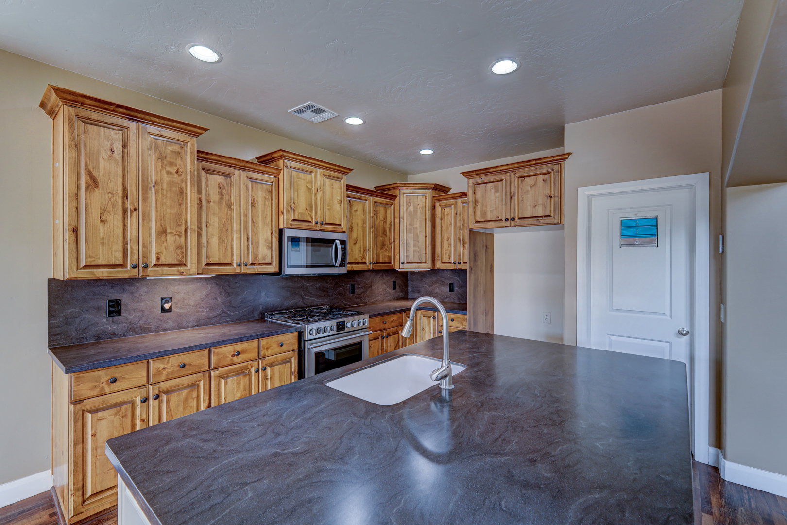 Kitchen featuring a large central island with an undermount sink and gooseneck faucet