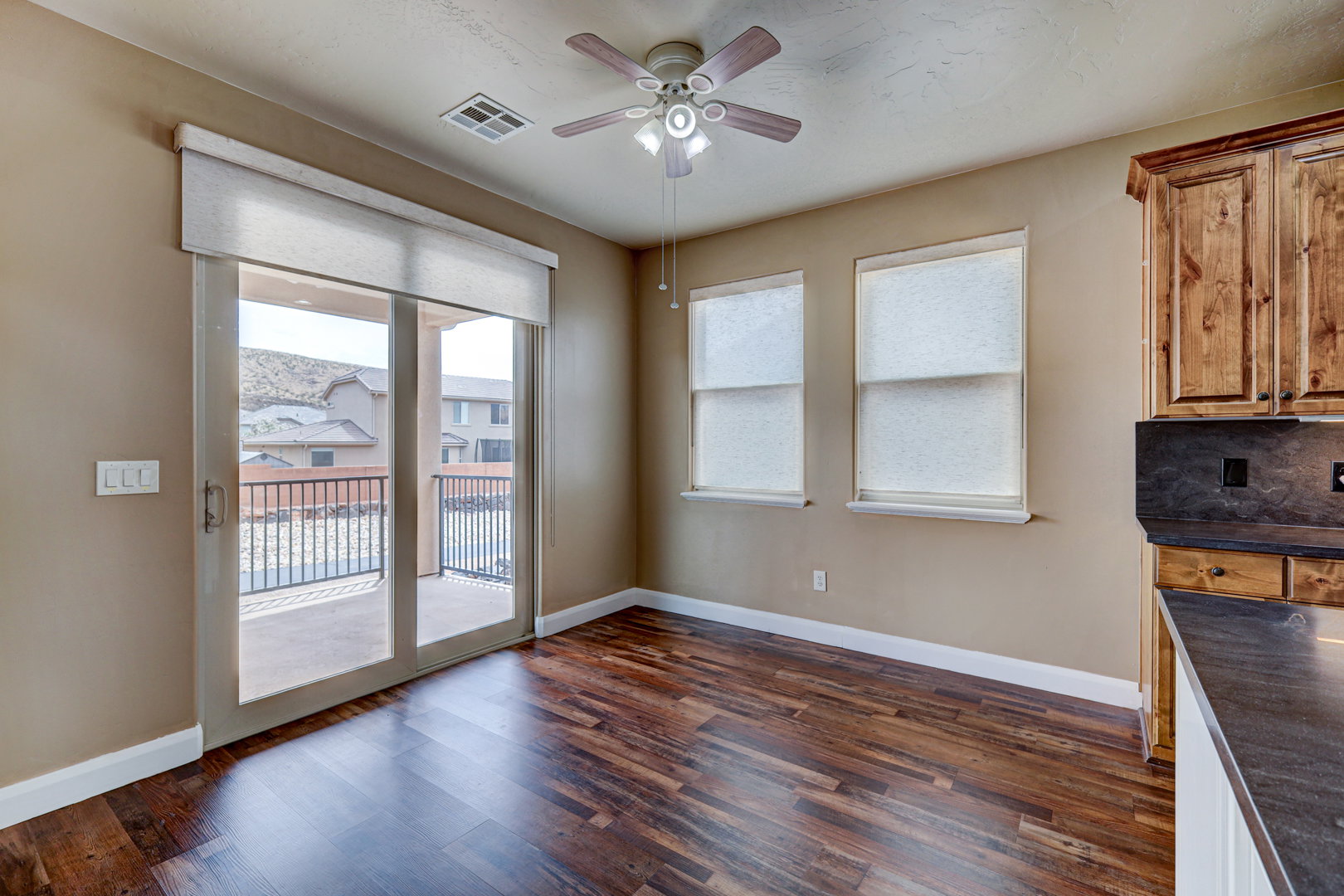 Spacious room featuring wood-finish flooring, neutral-toned walls, and a ceiling fan with integrated lighting