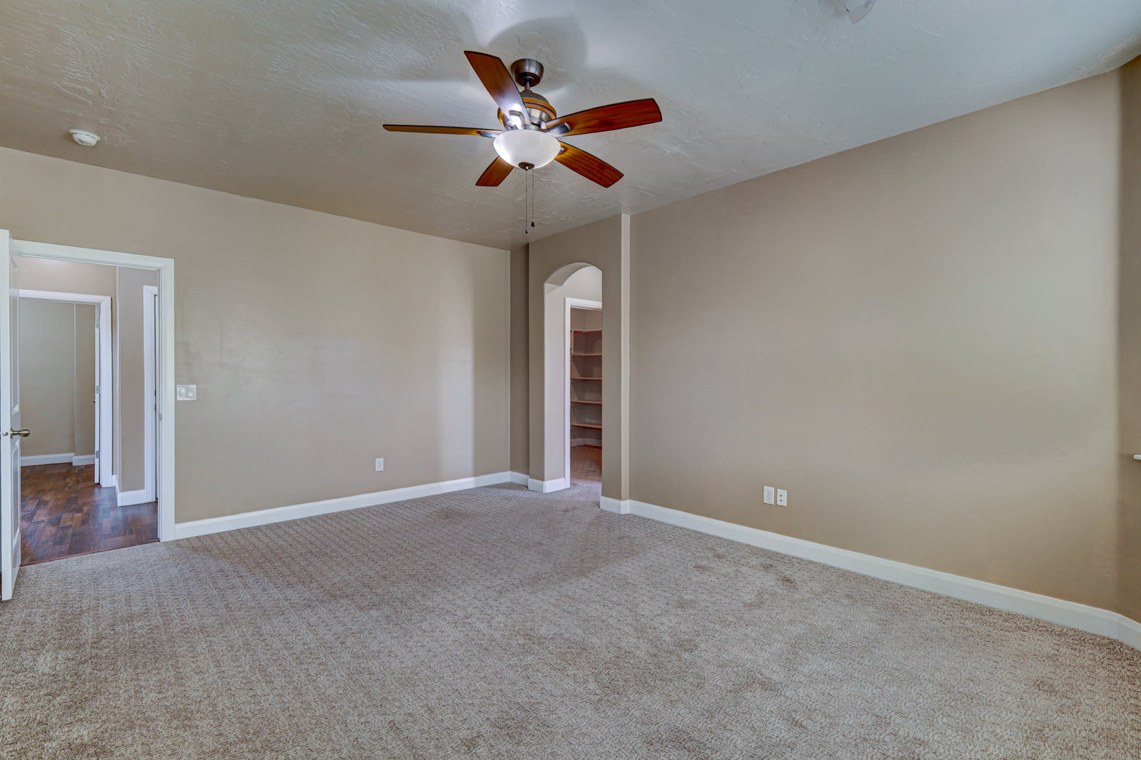 Spacious room featuring neutral carpeting, a ceiling fan with integrated lighting, and light-toned wall paint