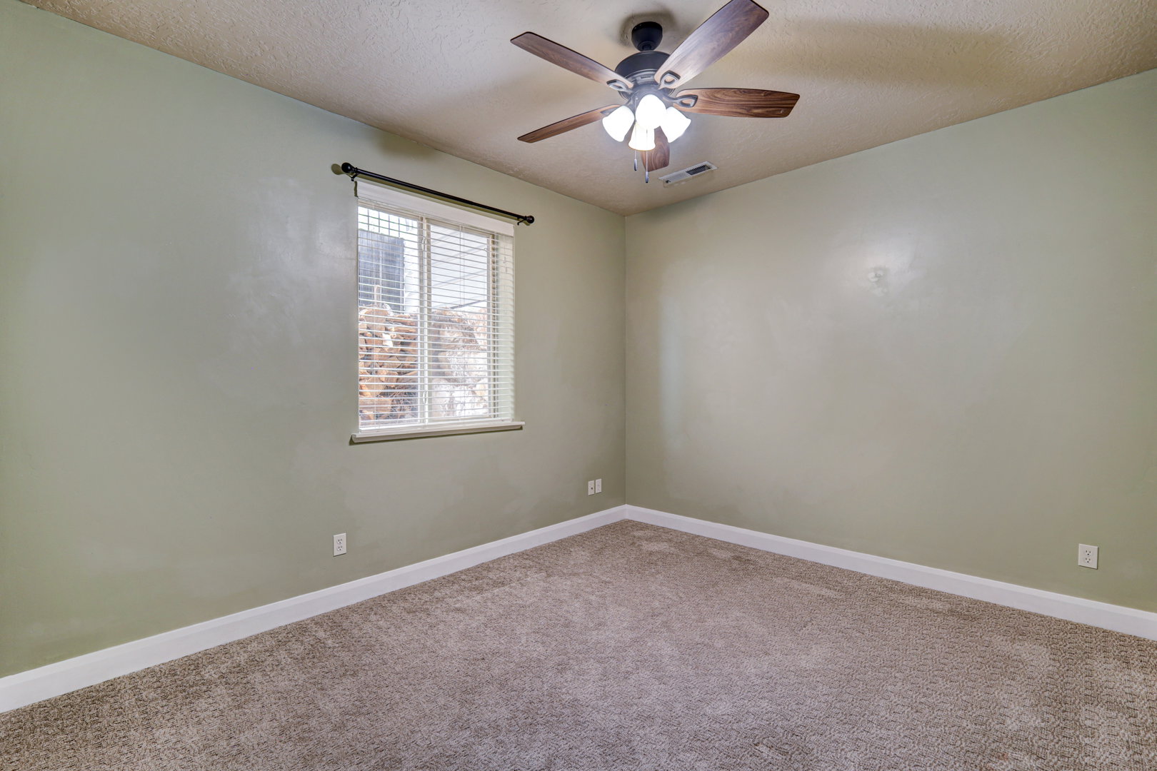 Bedroom featuring light green walls, a window with blinds, and a ceiling fan with integrated lighting