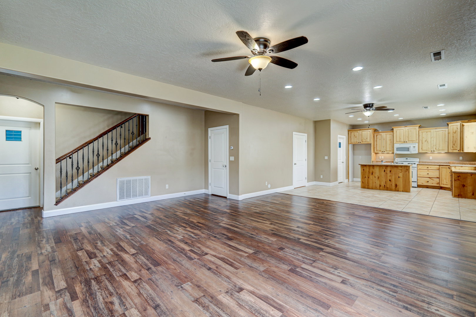 Spacious open-concept living area featuring wood-finish flooring, a ceiling fan, and recessed lighting