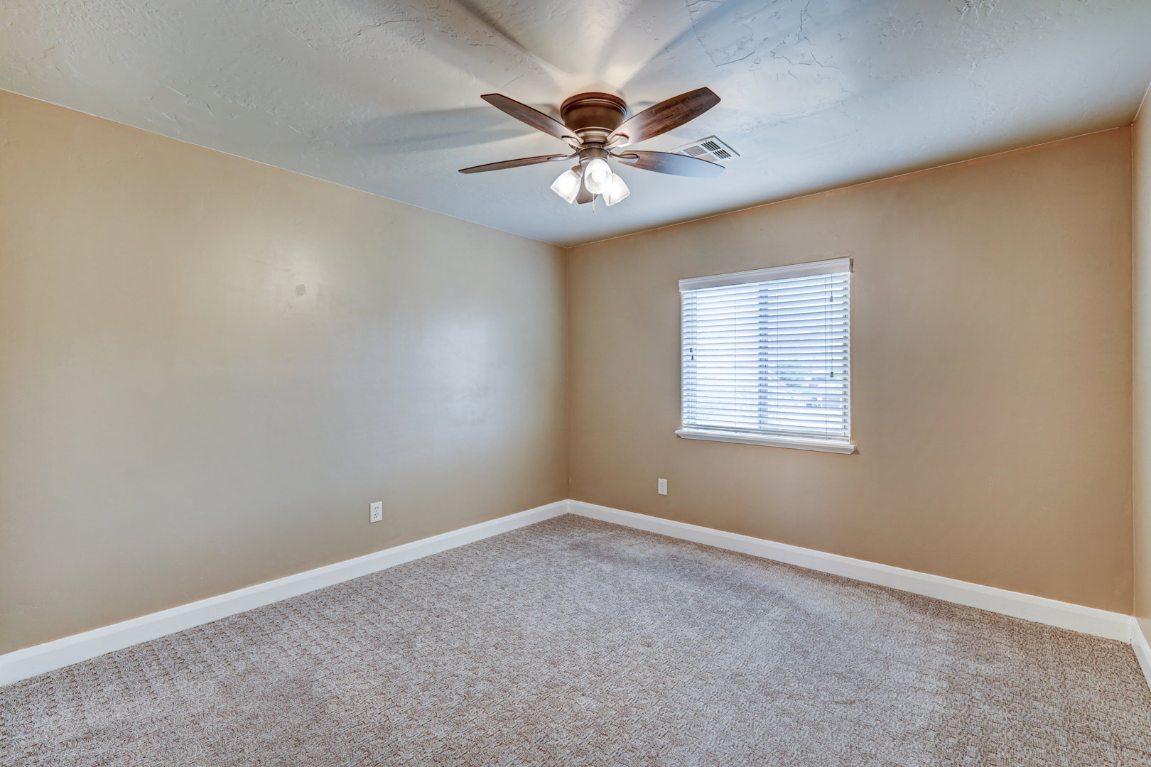 Neutral-toned room featuring light beige walls and a textured ceiling