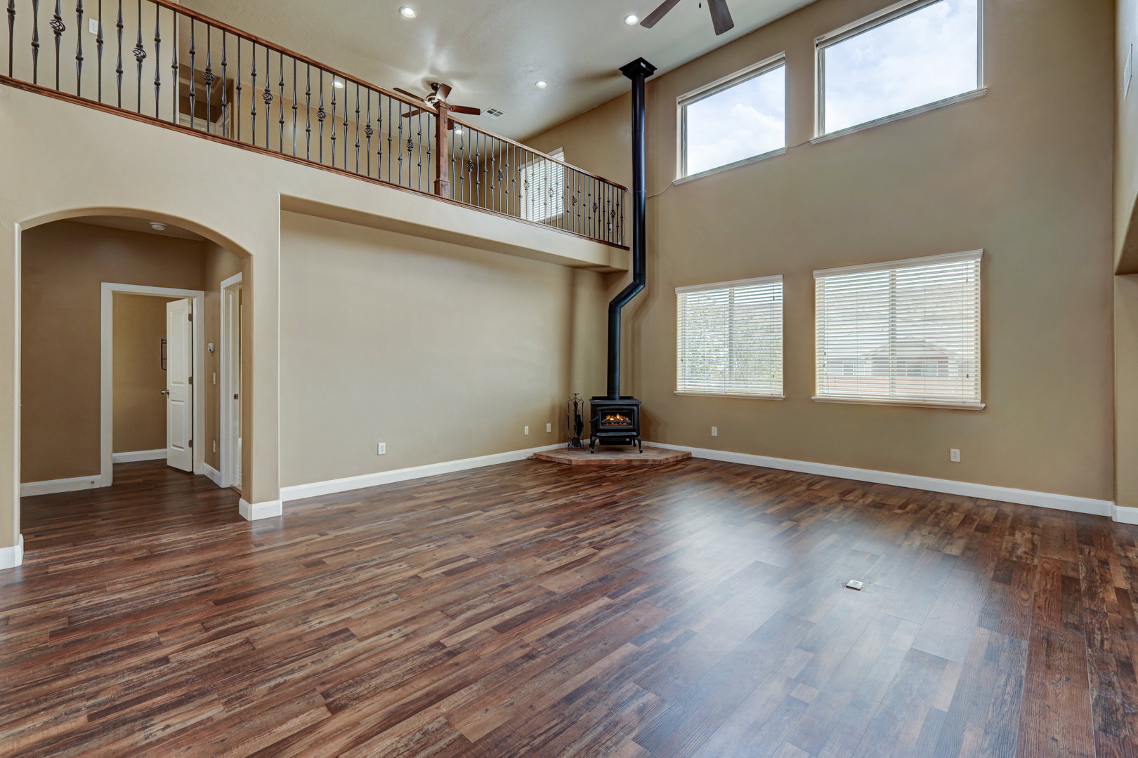 Spacious living area featuring wood-finish flooring, a freestanding wood-burning stove with a stovepipe, and a vaulted ceiling