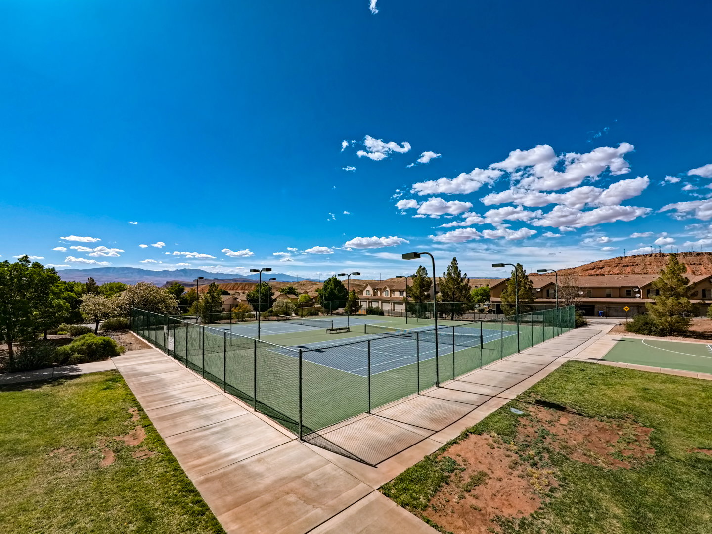 Community tennis courts featuring asphalt surfaces and surrounding fencing