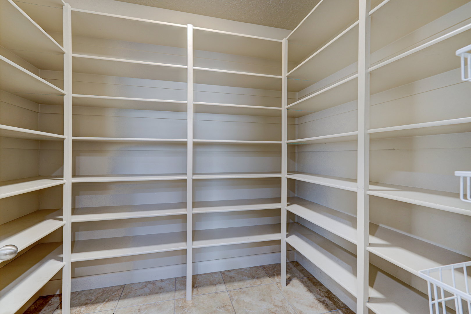 Built-in shelving units with adjustable shelves and a corner configuration, set against light-colored walls and tile flooring