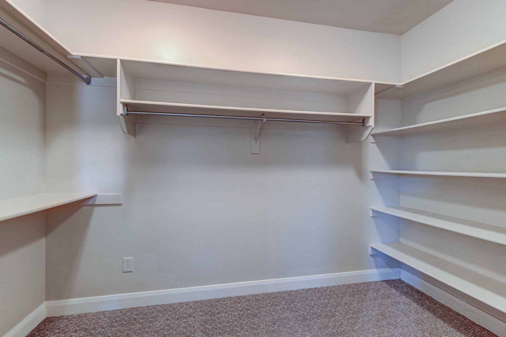 Walk-in closet featuring built-in shelving, multiple hanging rods, and neutral-toned carpeting