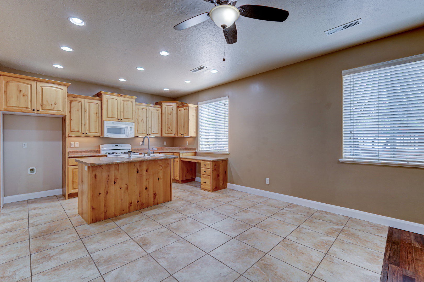 Kitchen with wood-finish cabinetry, a central island, and tile flooring