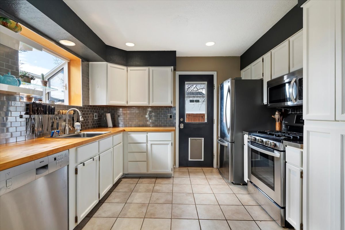 Kitchen featuring wood-finish countertops, white cabinetry, and stainless steel appliances